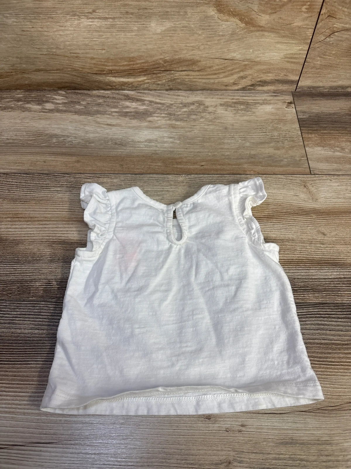 Front view of Baby Gap embroidered rabbit shirt showcasing ruffled sleeves and keyhole neckline on a wood floor