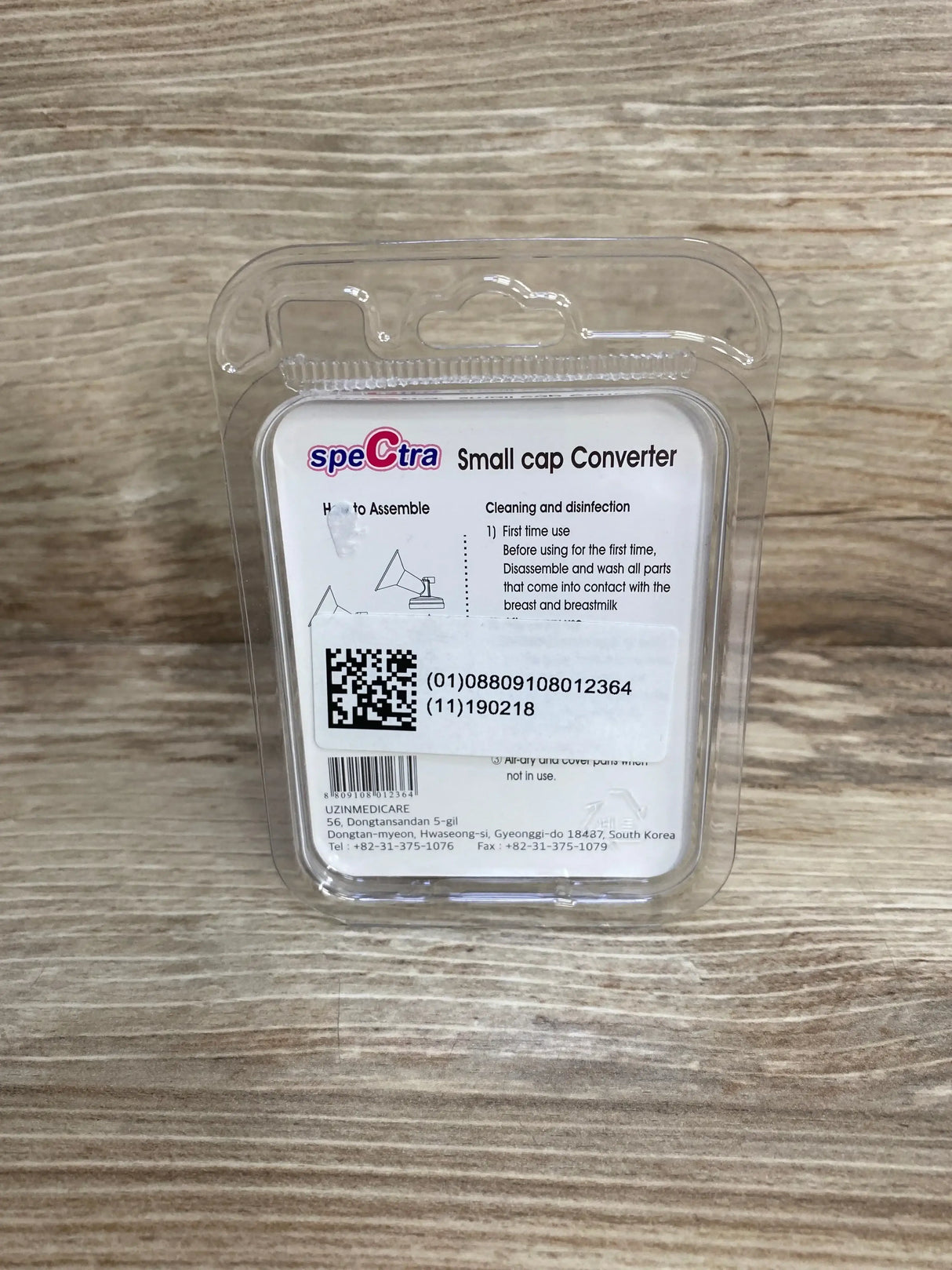 Front view of Spectra small-to-wide neck cap adapter packaging showing 'Small cap Converter' label and QR code on wood background