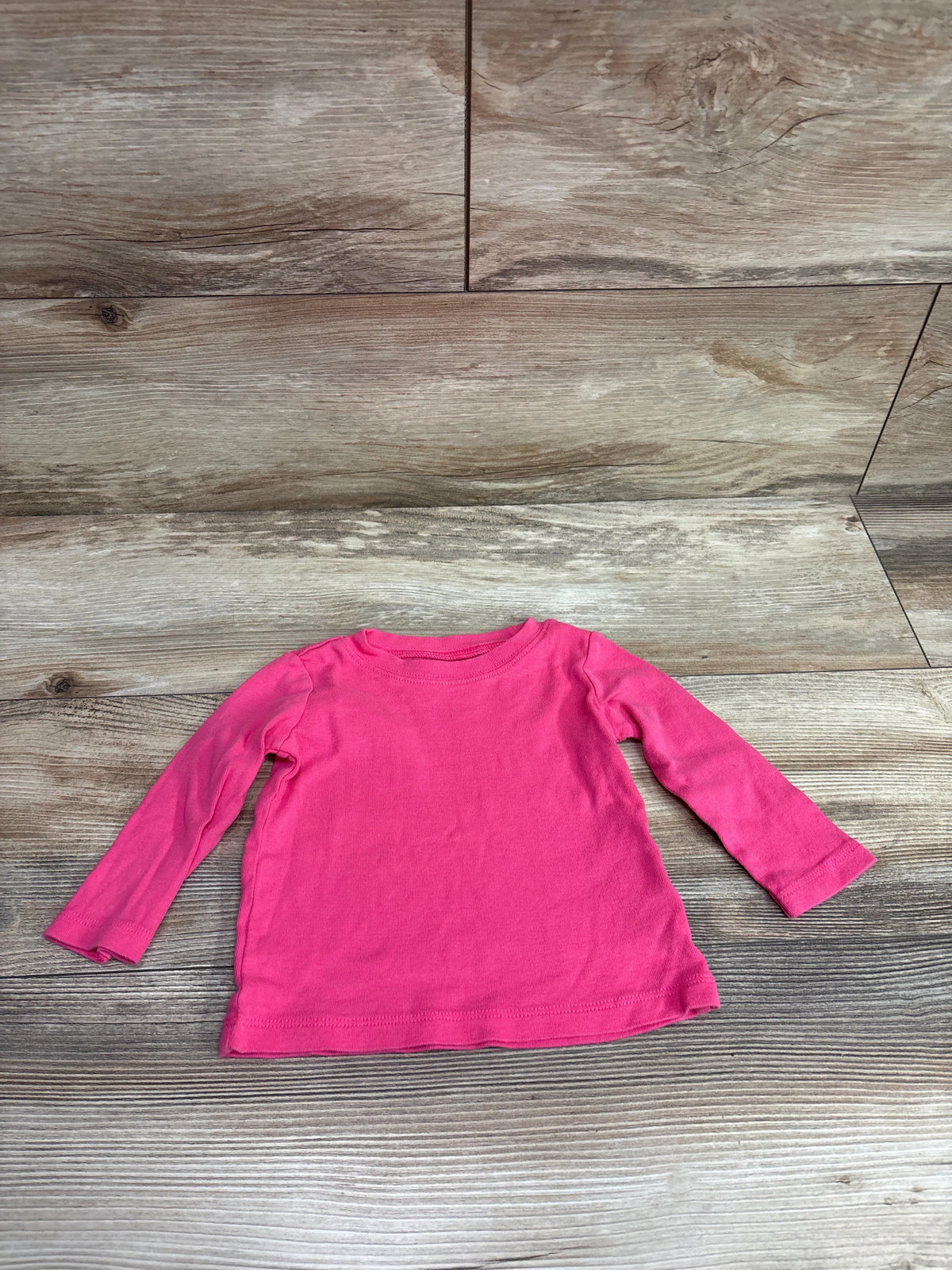 Carter's long sleeve pink shirt for baby size 6-9 months on a wooden background