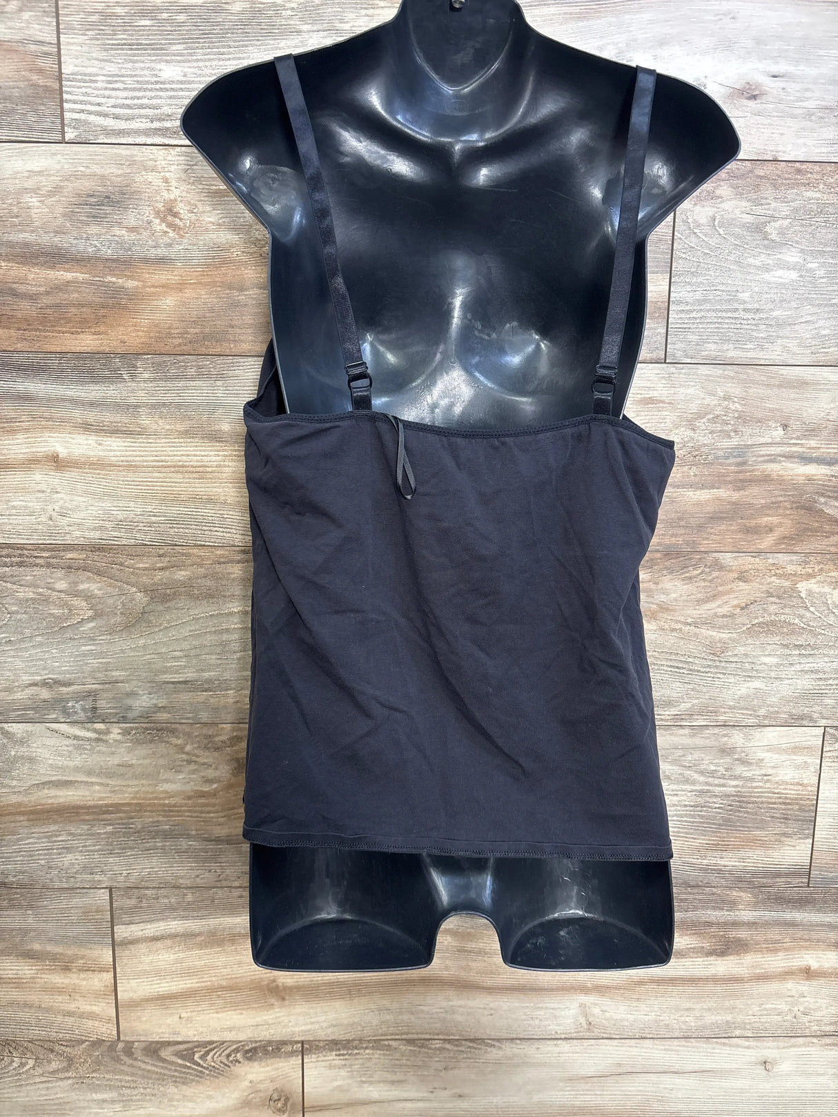 Front view of black maternity nursing tank top on a torso mannequin with adjustable shoulder straps on wood floor