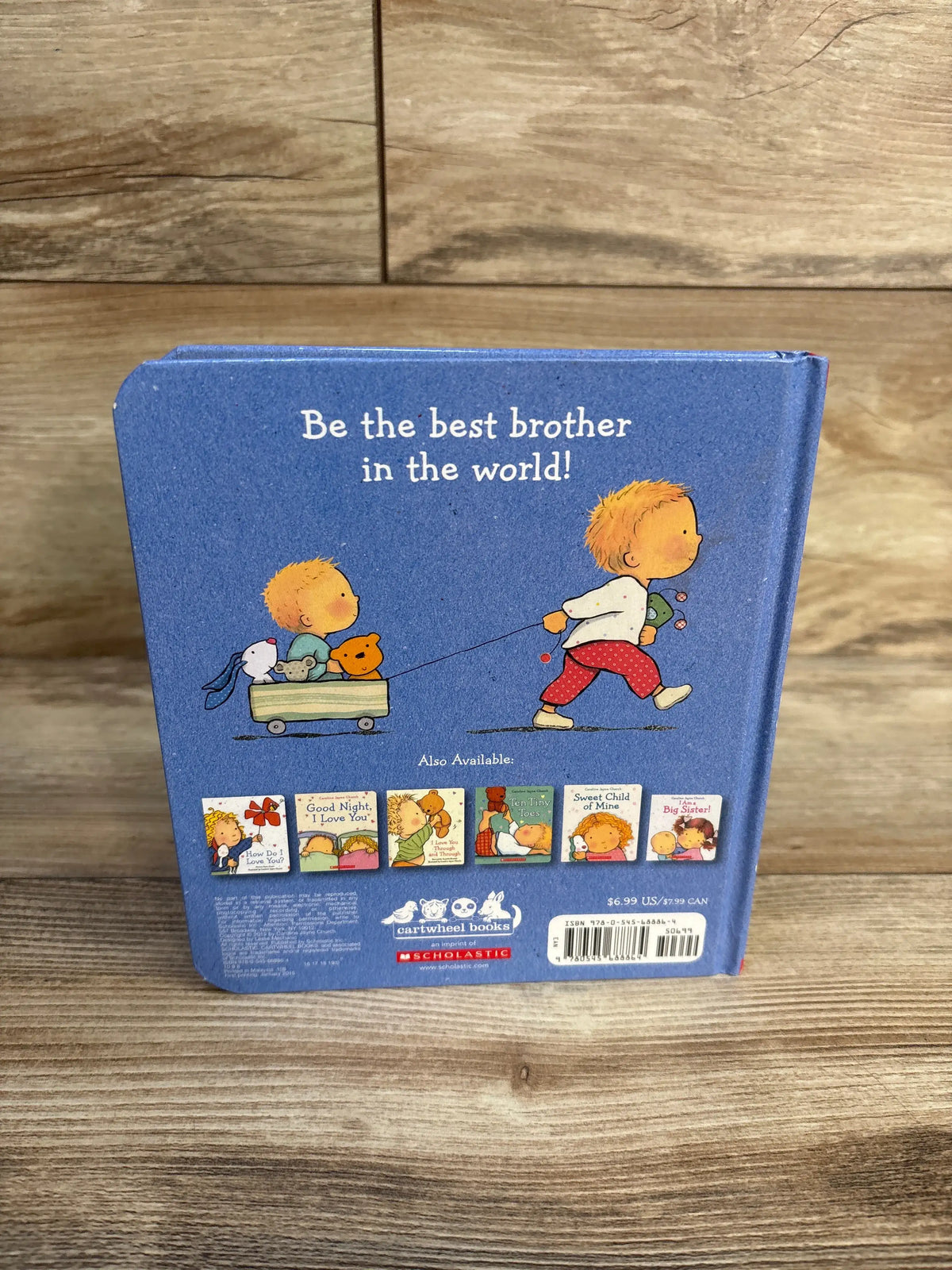 Back cover of I Am A Big Brother Hardcover Book showing an illustrated boy pulling a wagon with the headline Be the best brother in the world on a wood floor