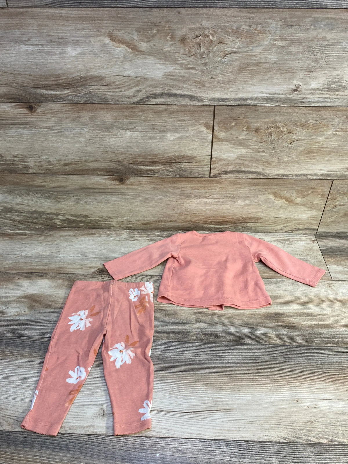 Flat lay of Carter’s 2pc pink button-top and floral leggings set, back of top and leggings on wood background