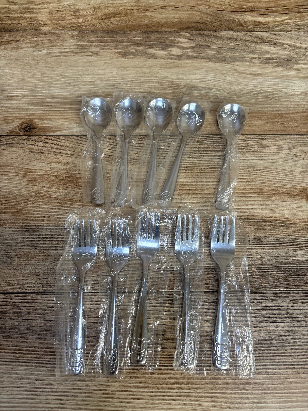 Stainless steel Hello Kitty forks and spoons in plastic wrap on wooden table