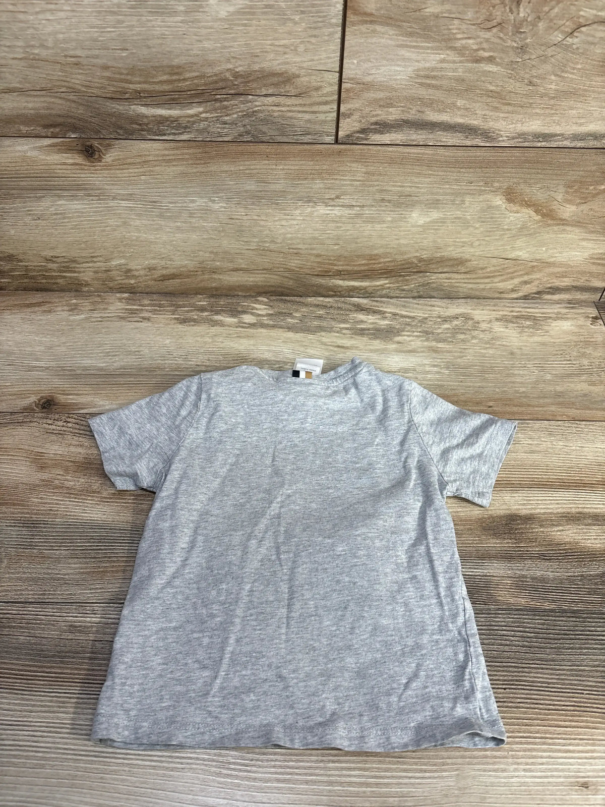 Flat lay of Boss Kidswear grey short-sleeve toddler T-shirt showing heather fabric and crew neckline on wood background