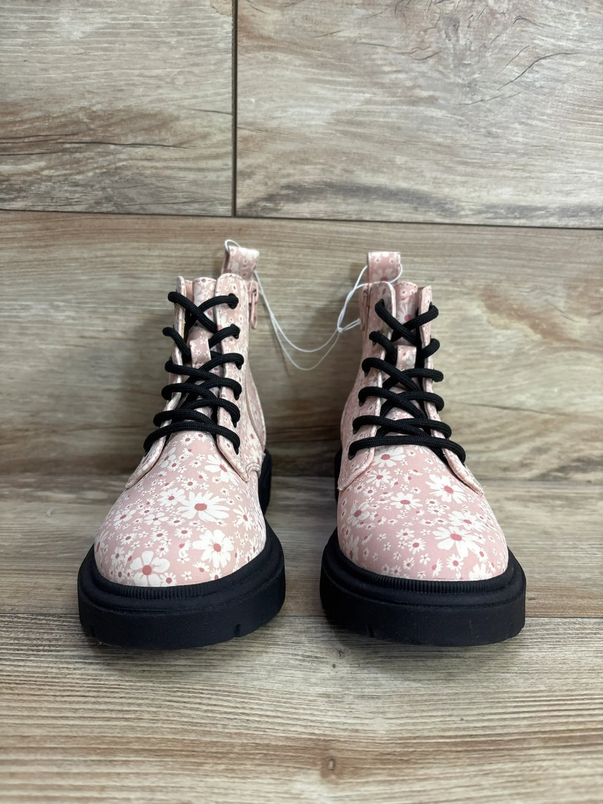 Pink floral kids lace-up boots with black soles on wood floor