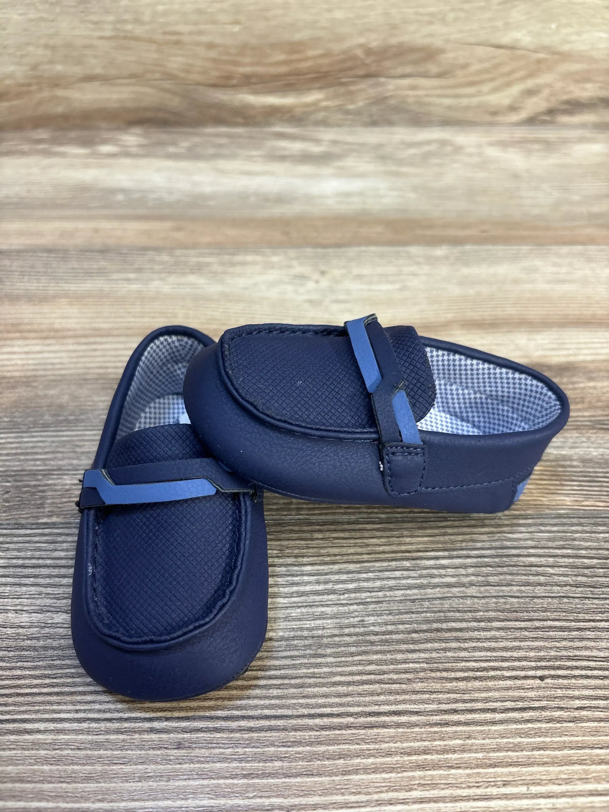 Navy blue baby loafers with textured sides on wooden background, kids shoes resale