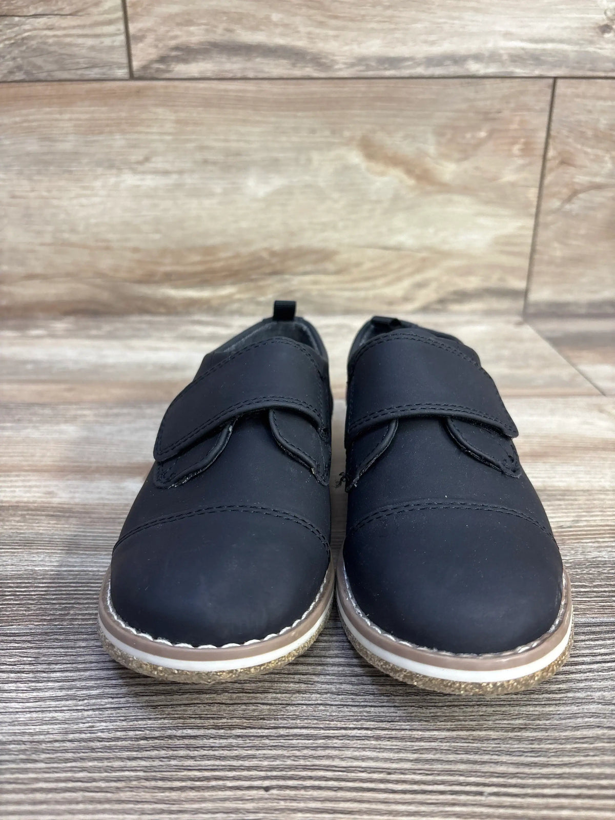 Front view of Cat & Jack Adonis derby shoes in black size 12C showing hook and loop strap and rounded toe on wood-look background