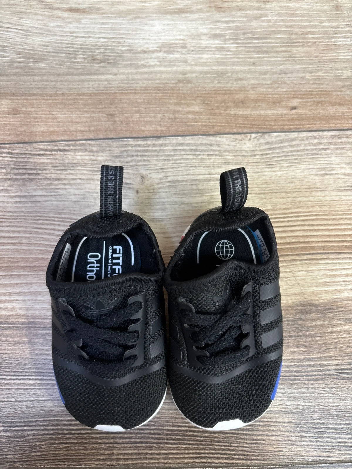 Front view of Adidas NMD Soft Sole Sneakers showcasing black textile uppers and elastic laces on wood flooring