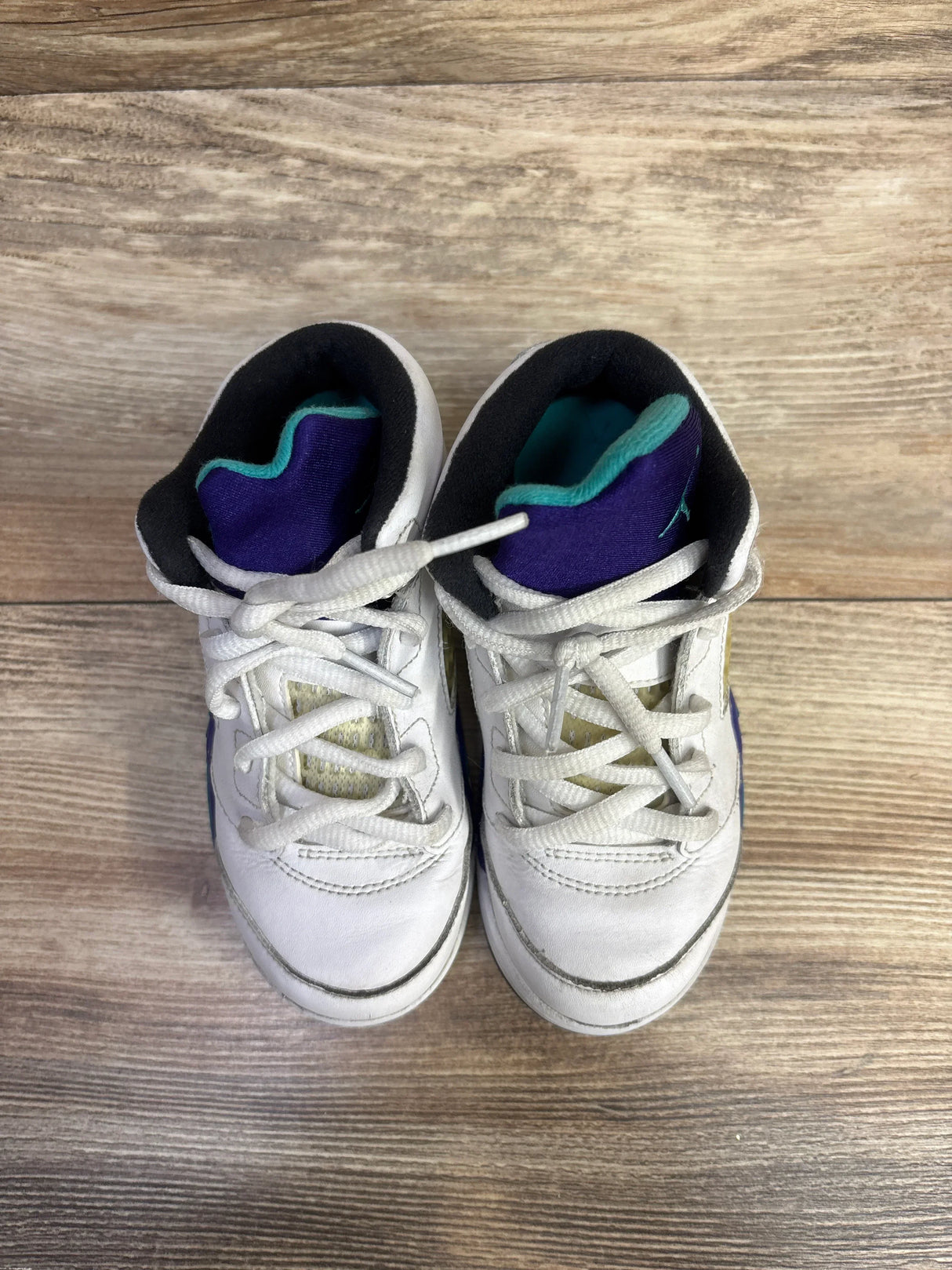 Top view of Air Jordan 5 Retro TD 'Grape' sneakers size 10C showing white leather with purple and teal accents and light wear on a wooden floor