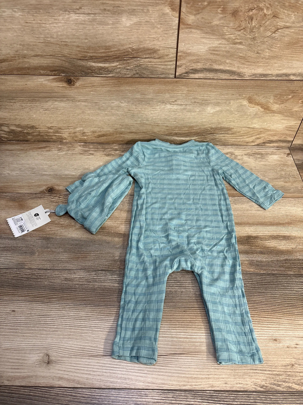 Overhead view of a blue jacquard striped romper and matching hat showcasing long sleeves and striped texture on a wood-look background