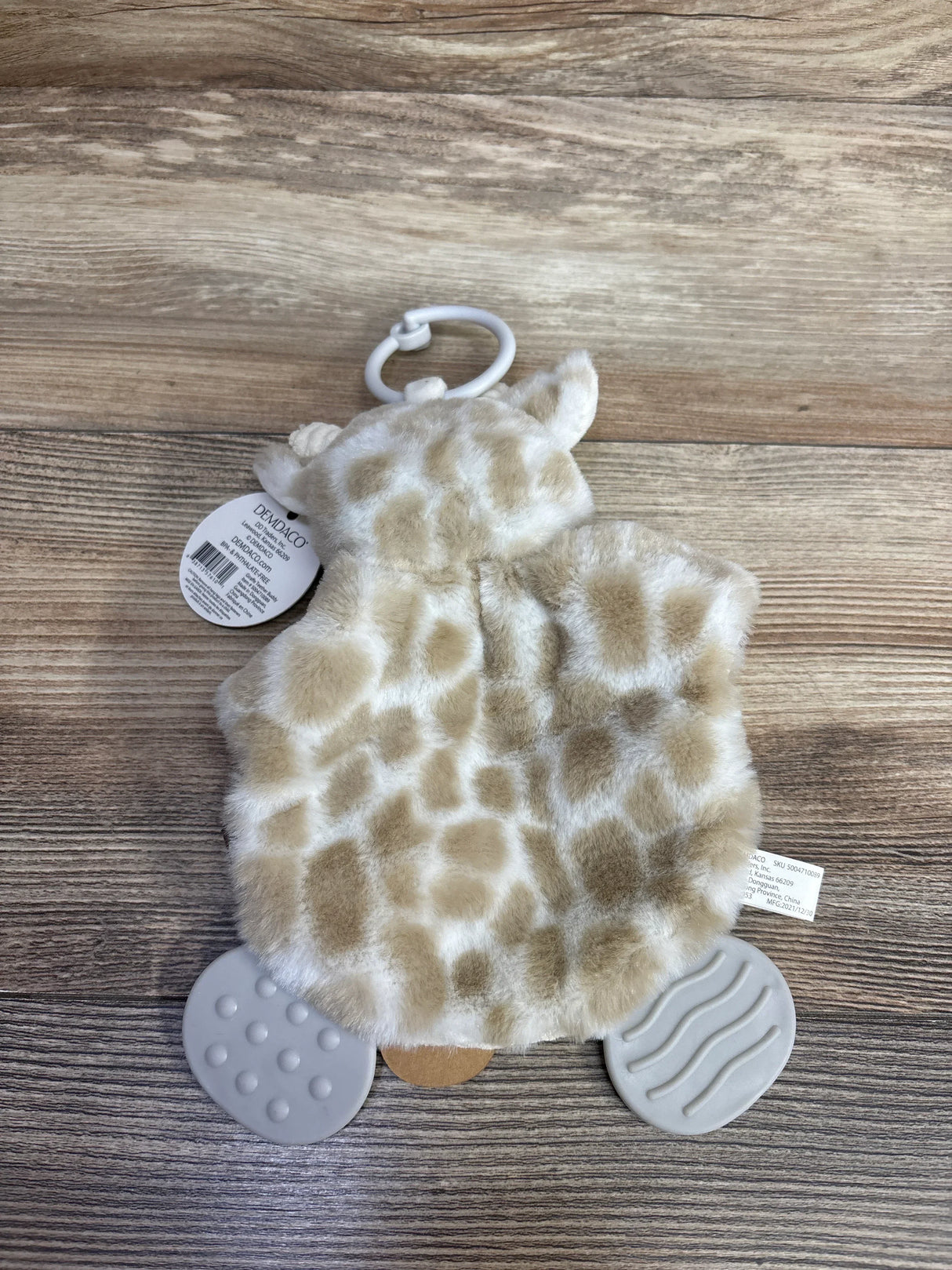Plush giraffe baby toy with clip and textured teether feet on wood background