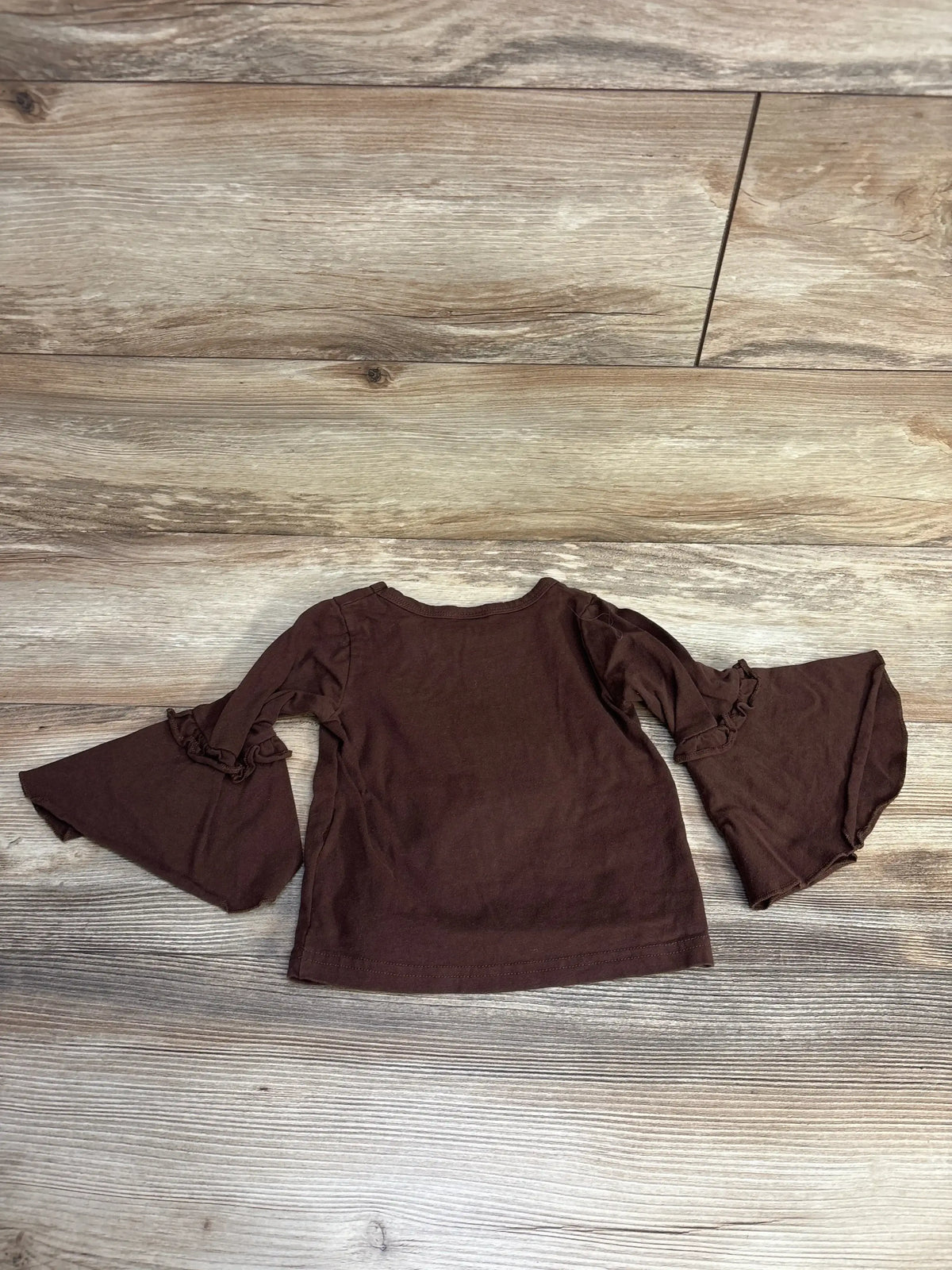 Brown long sleeve toddler shirt with ruffled bell sleeves on wooden floor