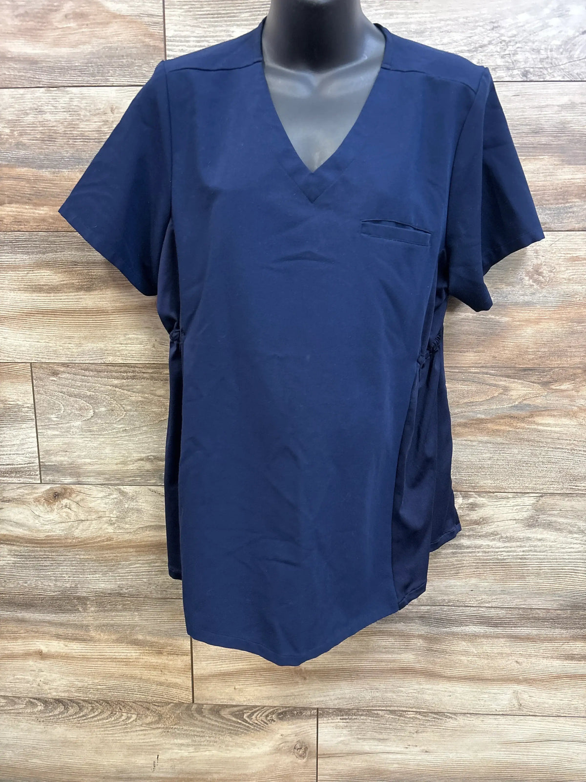 Front view of Mandala one-pocket maternity scrub top showcasing navy fabric, V-neck, short sleeves, and side ruching on a mannequin