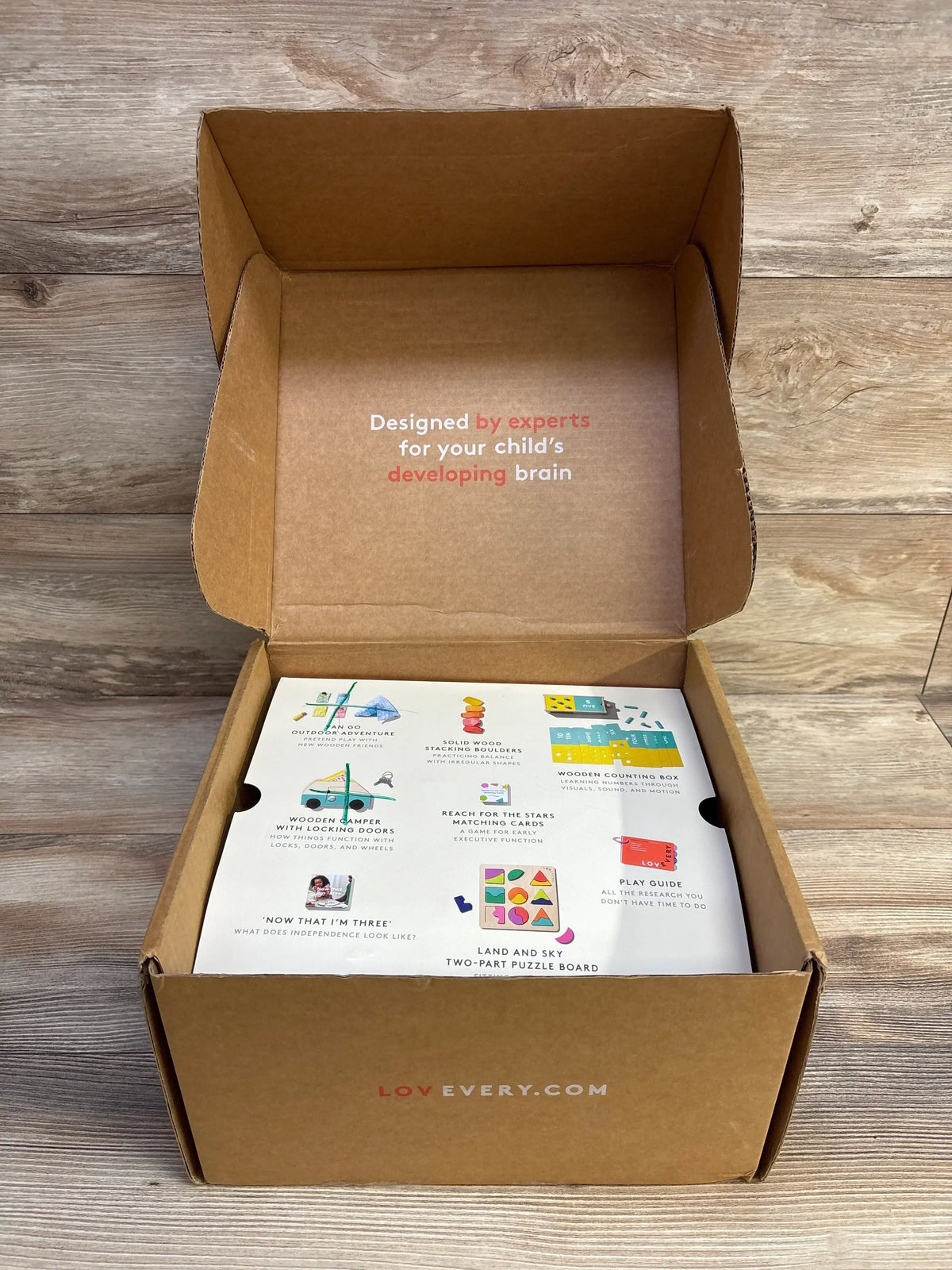 Top view of Lovevery play kit box open, lid reads Designed by experts for your child’s developing brain, contents visible