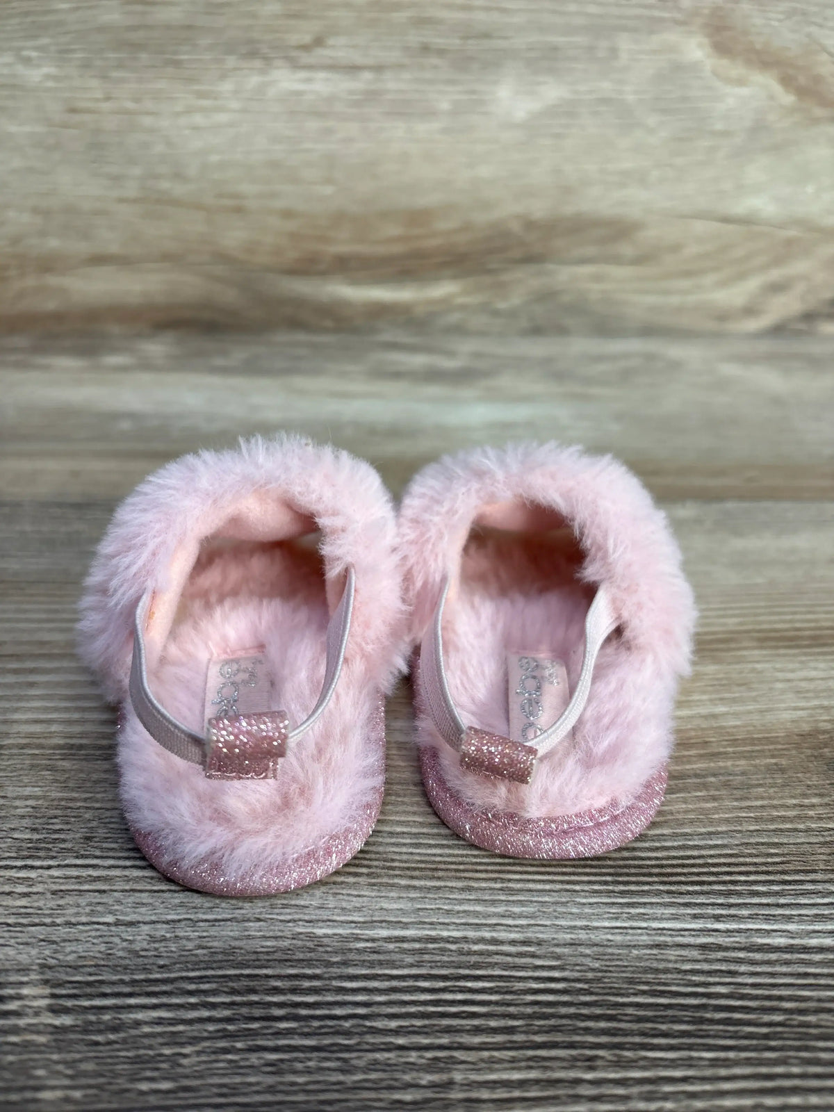 Pair of pink faux fur slide sandals for kids with glittery soles and straps.