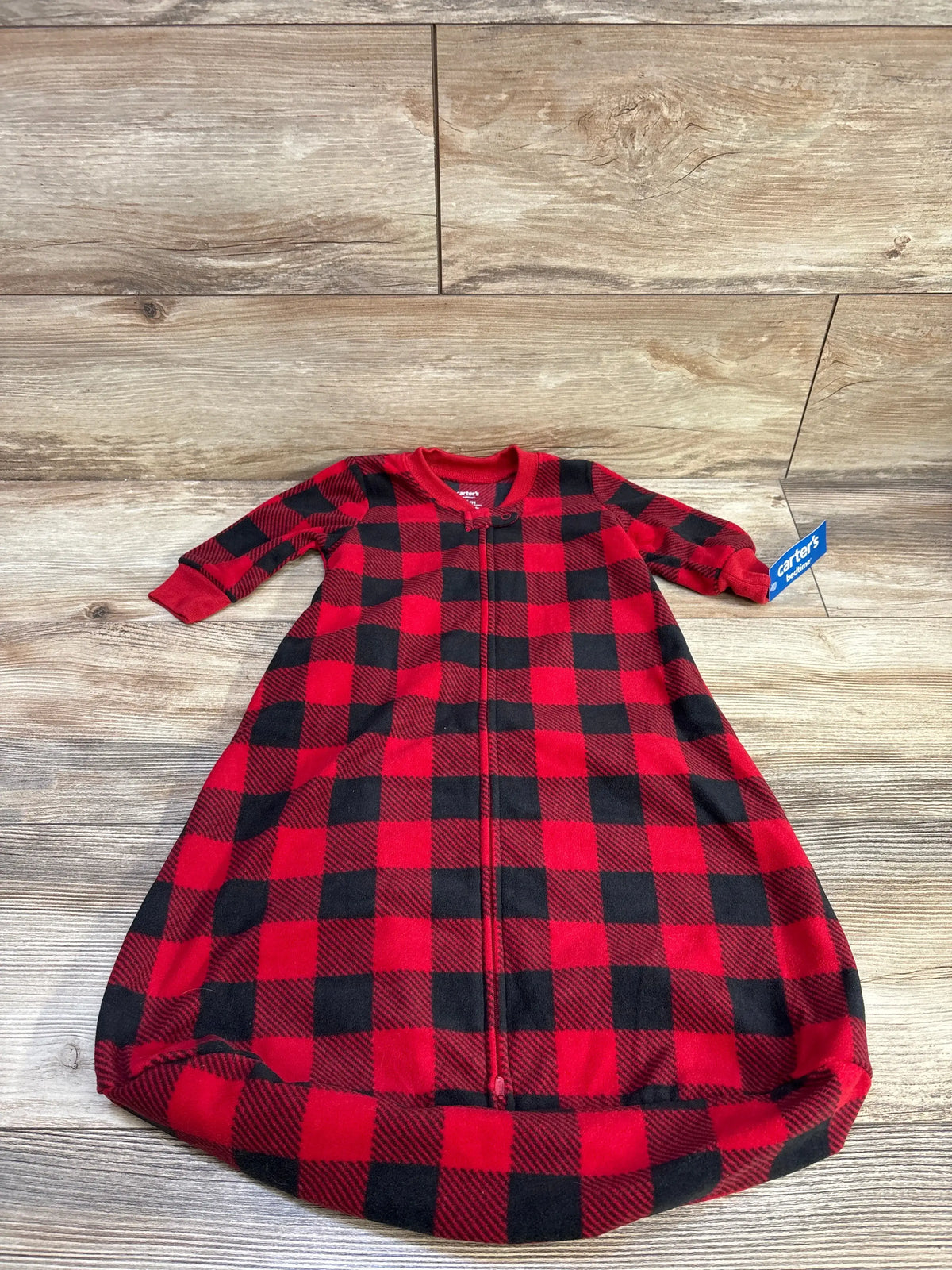 Front view of Carter’s red buffalo plaid sleep sack, size 3-6 months, showcasing long sleeves and front zipper on a wood-look floor