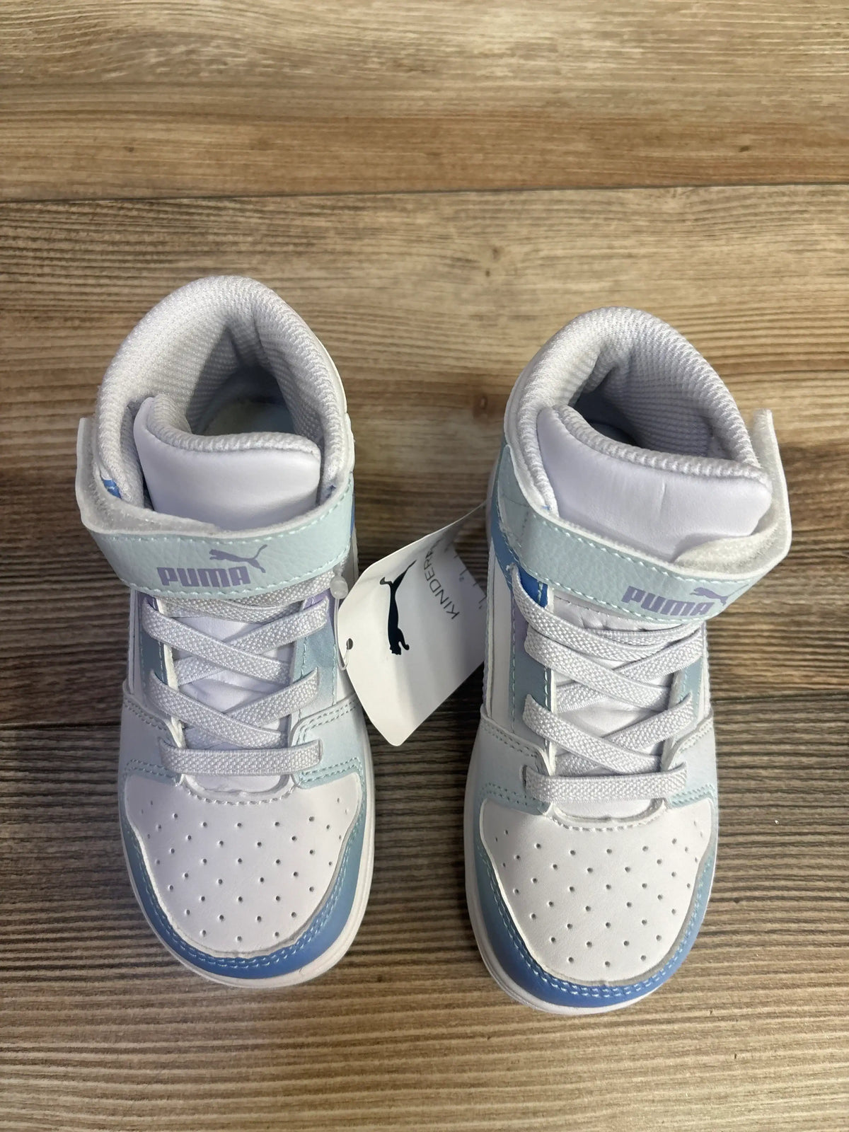 Pair of white and light blue Puma toddler sneakers on wooden floor with Puma tag