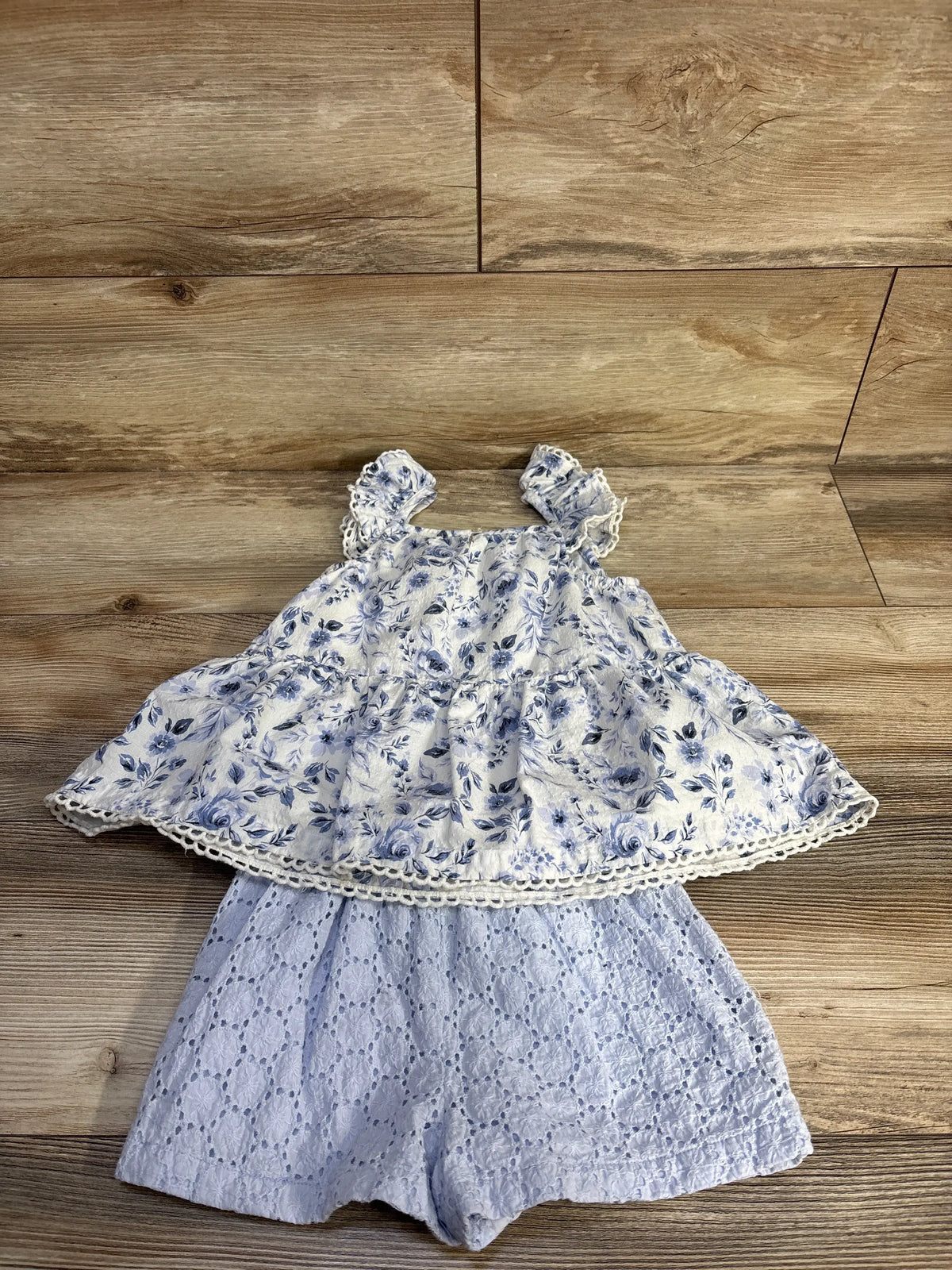 Flat lay of Joie Blue Floral Blouse and Lace Short Set, size 4T, showing sleeveless top and lace shorts on wood floor