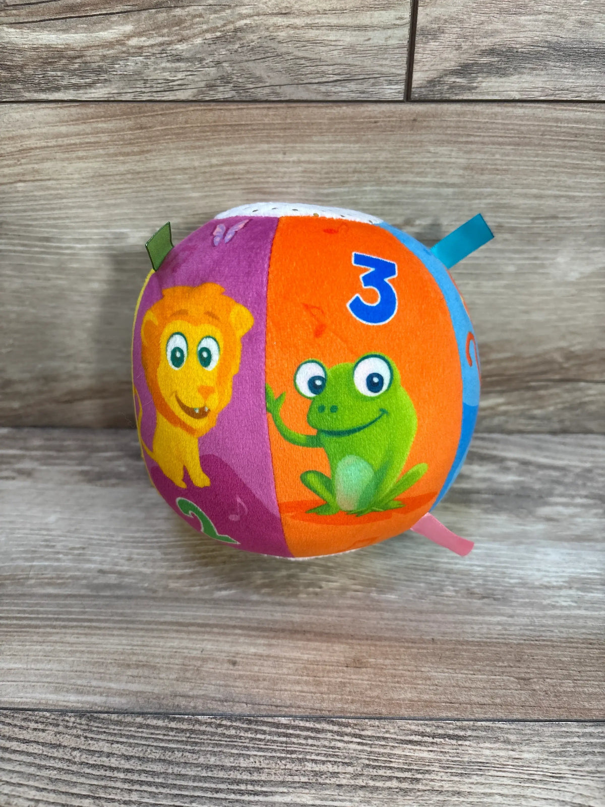 Front view of Move2Play Interactive Soft Ball showcasing colorful plush panels with animal graphics and number 3 on a wood surface