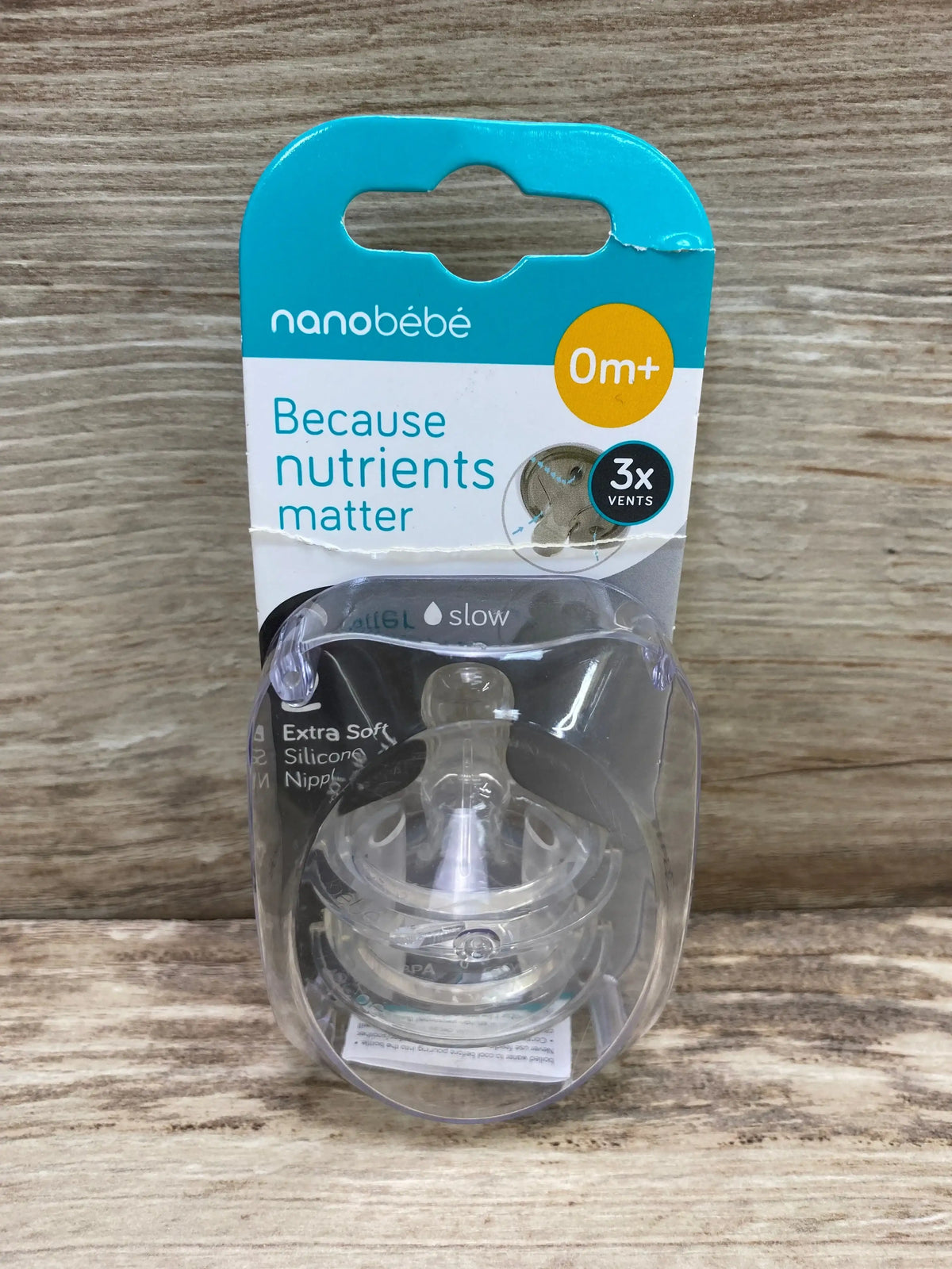 Front of Nanobebe slow-flow silicone nipple 2-pack showing extra-soft silicone, 0m age label and 3x vents on wood