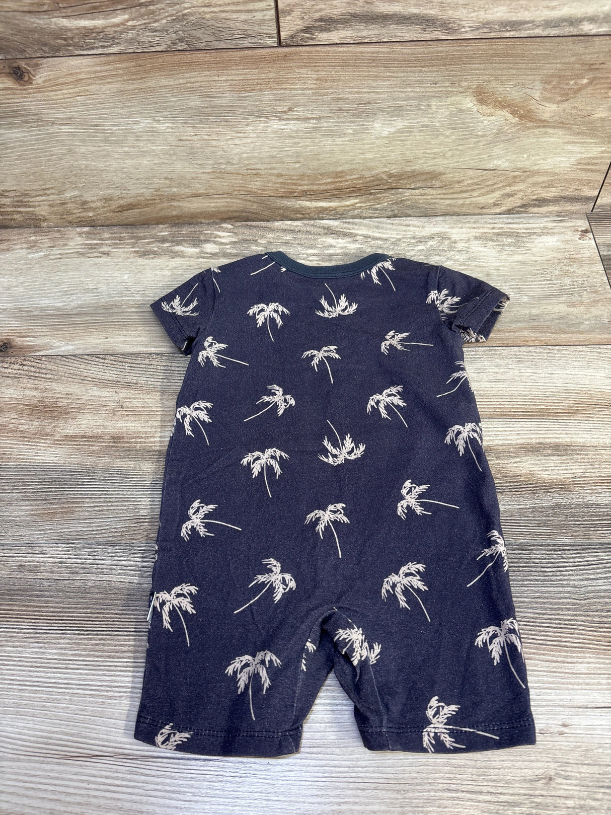 Back view of grey baby shortie romper (12m) with white palm tree print and short sleeves on wood background