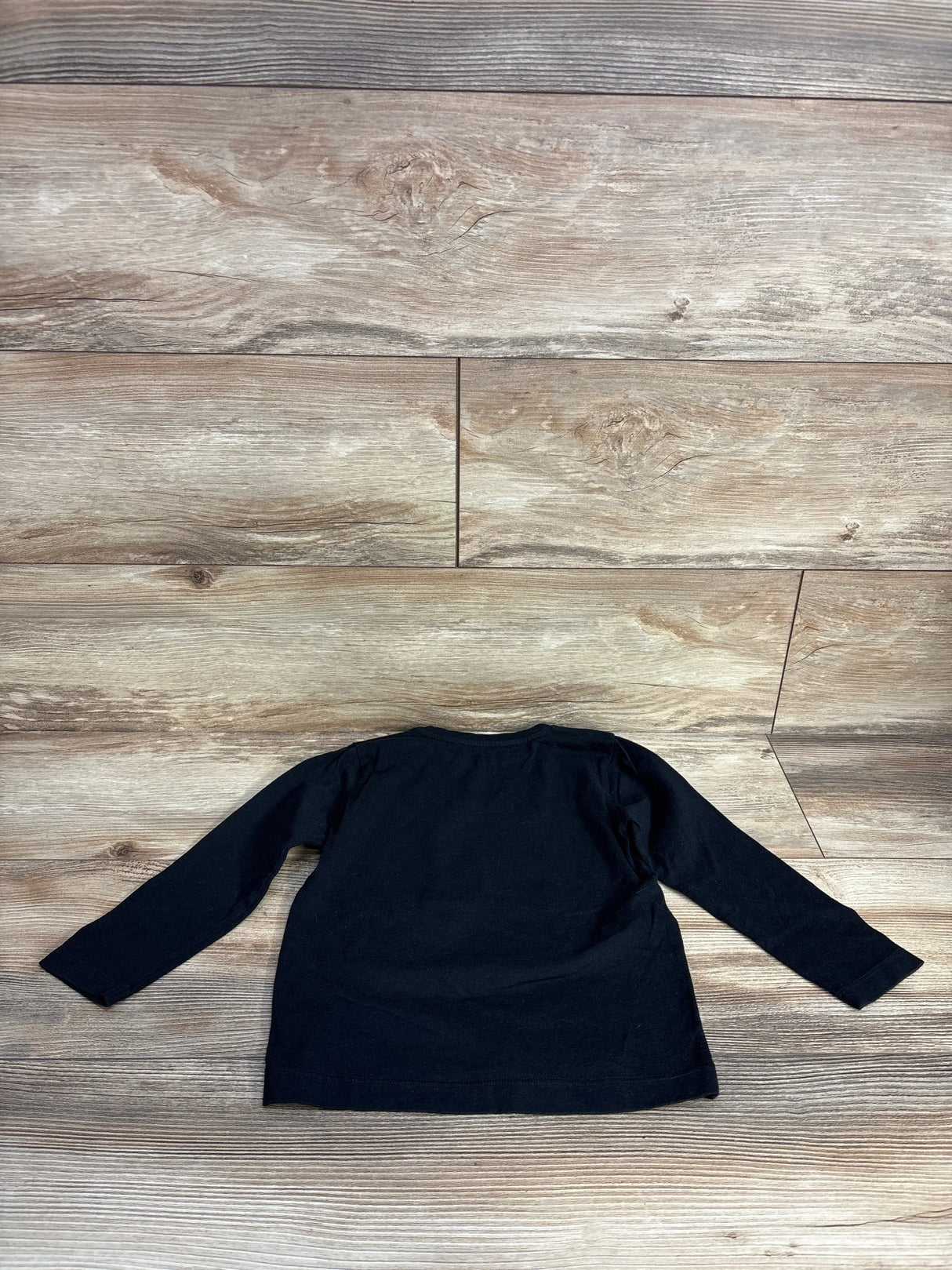 Black long sleeve shirt laid flat on wooden floor background