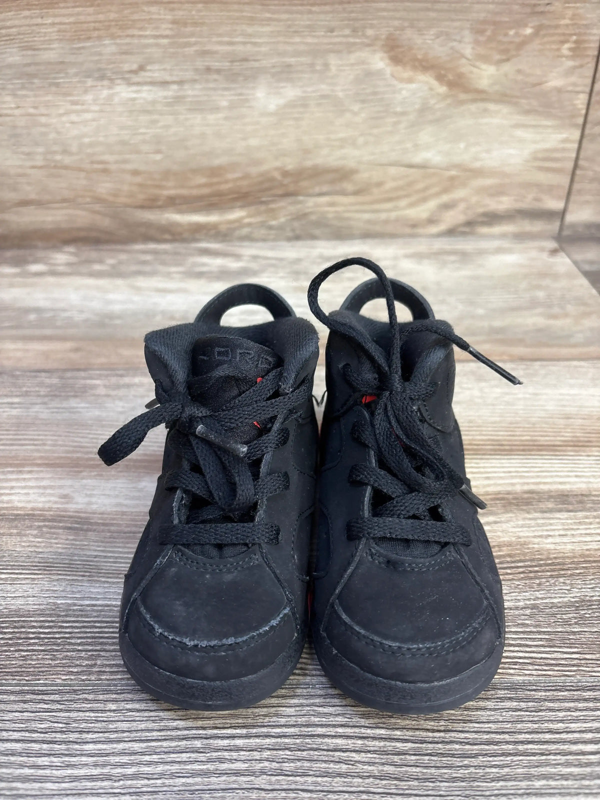 Front view of Air Jordan 6 Retro TD ‘Infrared’ sneakers showing perforated suede uppers and heel pulls on a wood floor