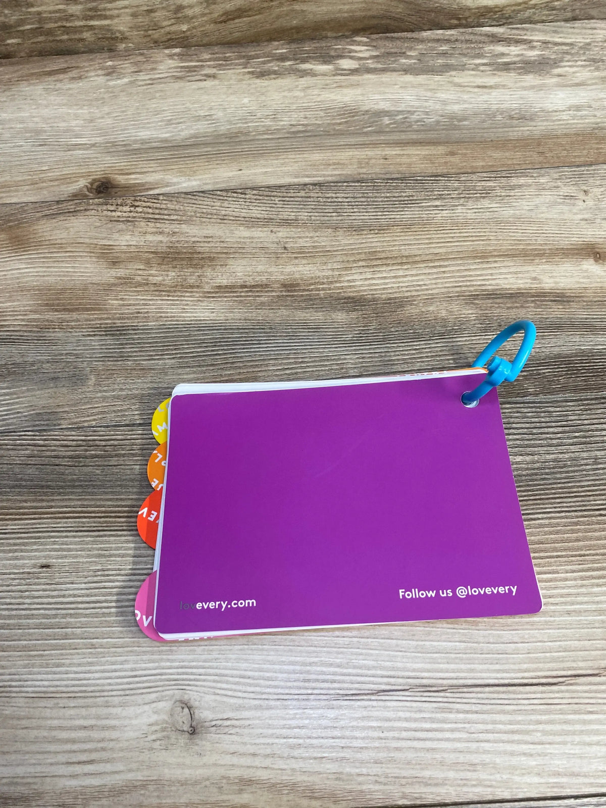 Lovevery purple flash card set with blue ring on wood table, colorful tab dividers visible