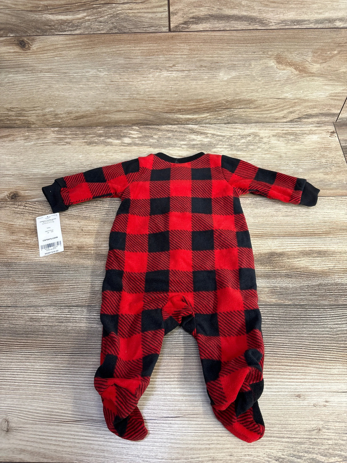 Red and black plaid baby sleeper footed pajamas on wooden background