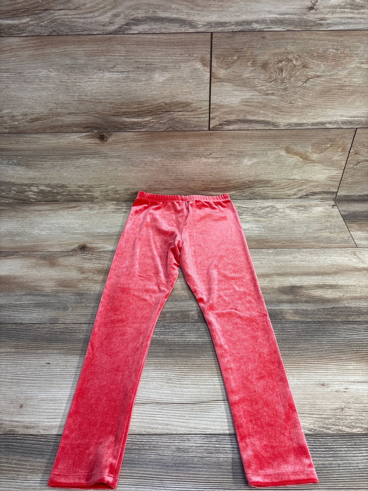 Pink velvet kids leggings on wooden background, children's clothing resale