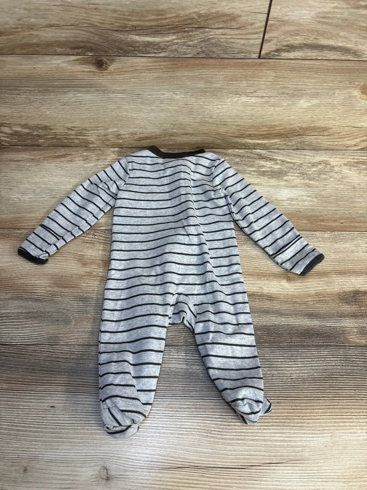 Gray and black striped baby footed pajamas on wooden floor