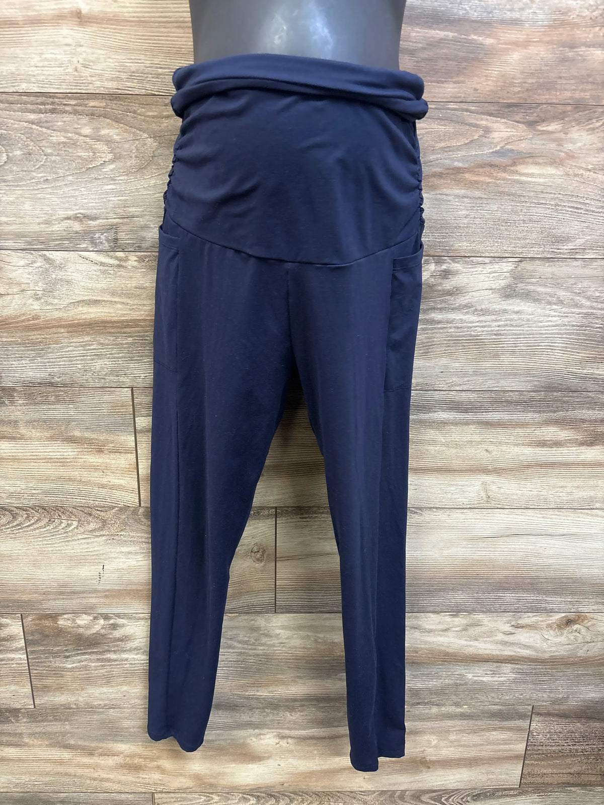 Front view of navy maternity ruched over-belly leggings showcasing the gathered panel and full-length legs on a wood floor