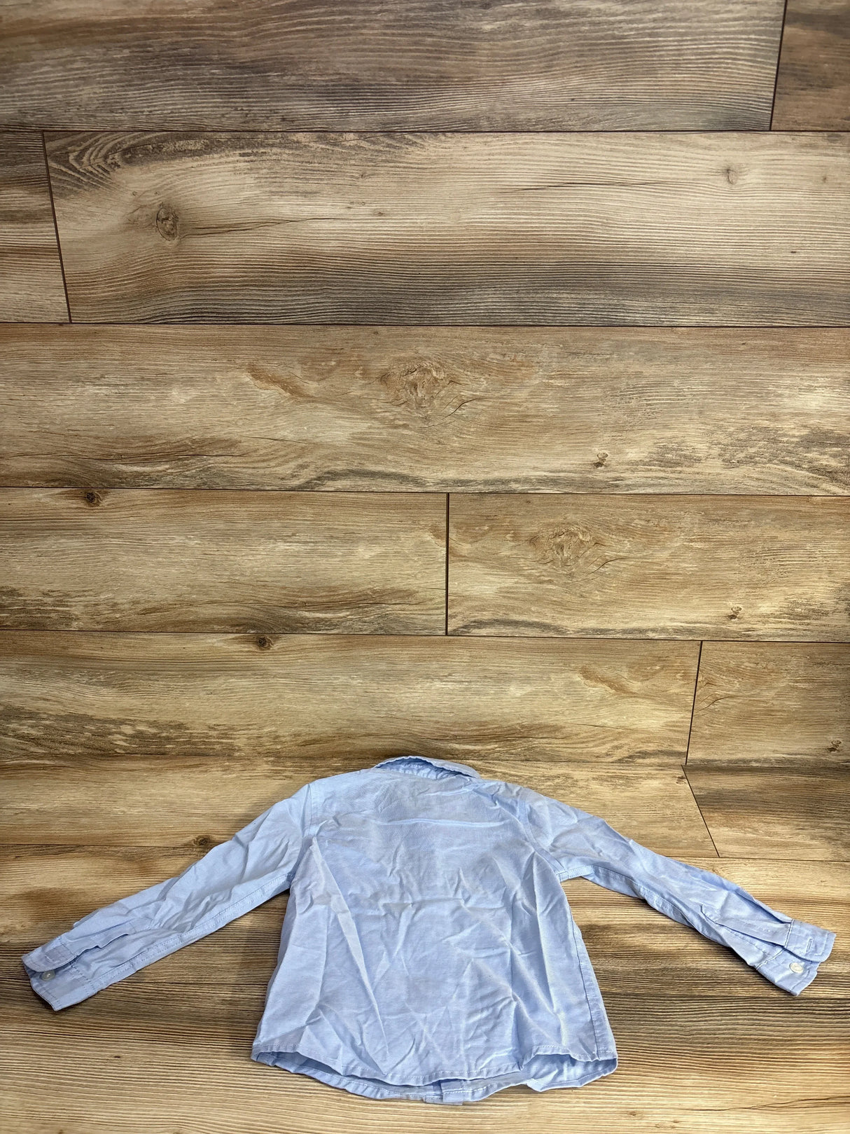 Light blue long sleeve children's dress shirt displayed on wood floor
