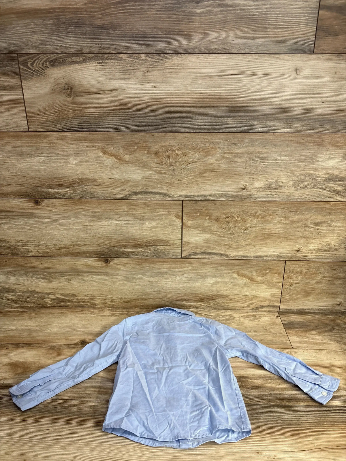 Light blue long sleeve children's dress shirt displayed on wood floor