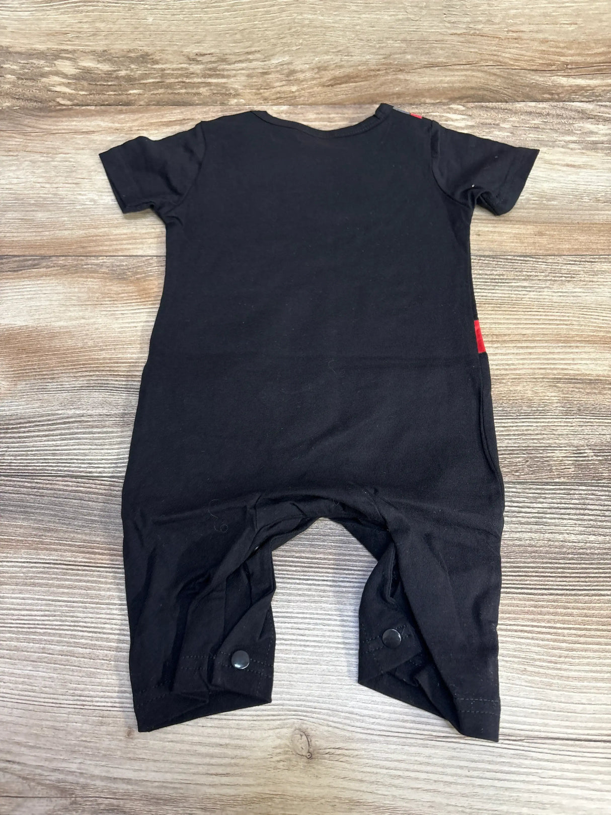 Front view of A&J Designs Ninja Romper in black, size 9-12 months, with short sleeves and snap closures on wood-grain background