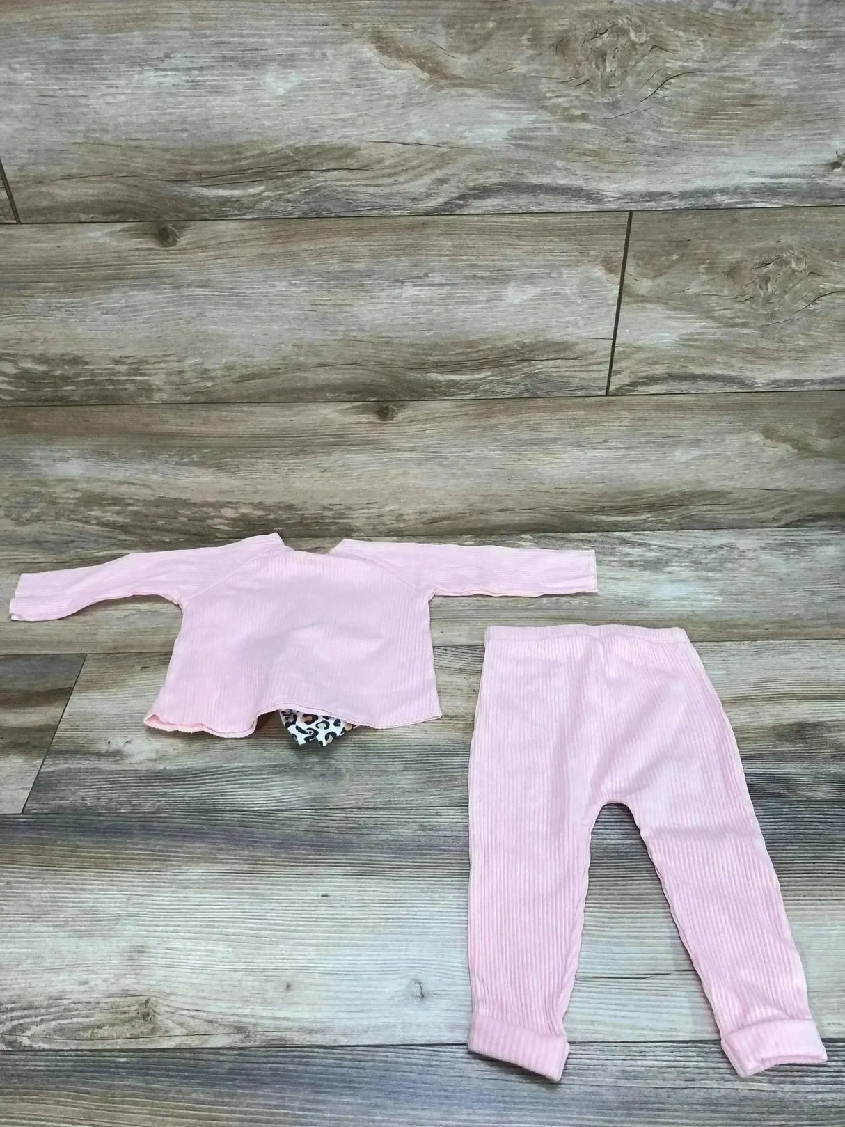 Flat-lay of Mudpie 3-piece pink ribbed set: long-sleeve top, matching leggings, and leopard-print diaper cover on wood floor