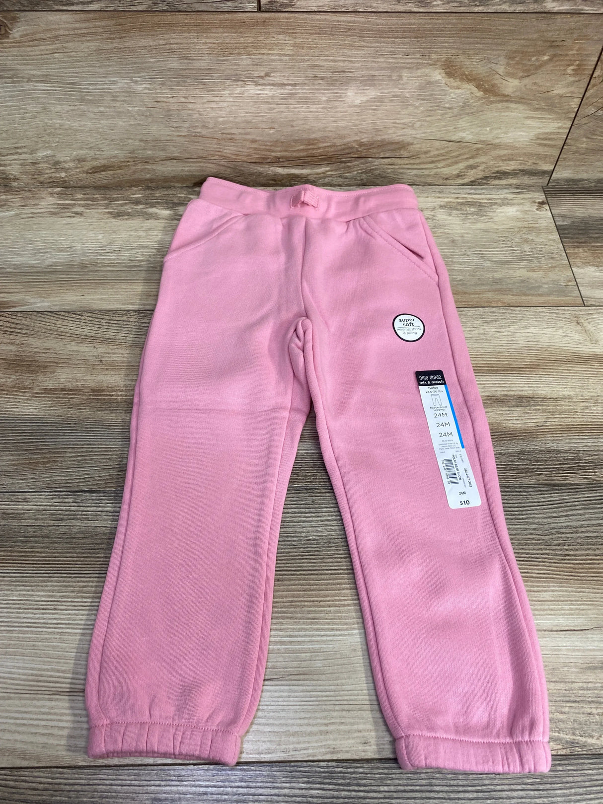 Pink toddler sweatpants with pockets and tags on wooden floor, size 24M, super soft fabric