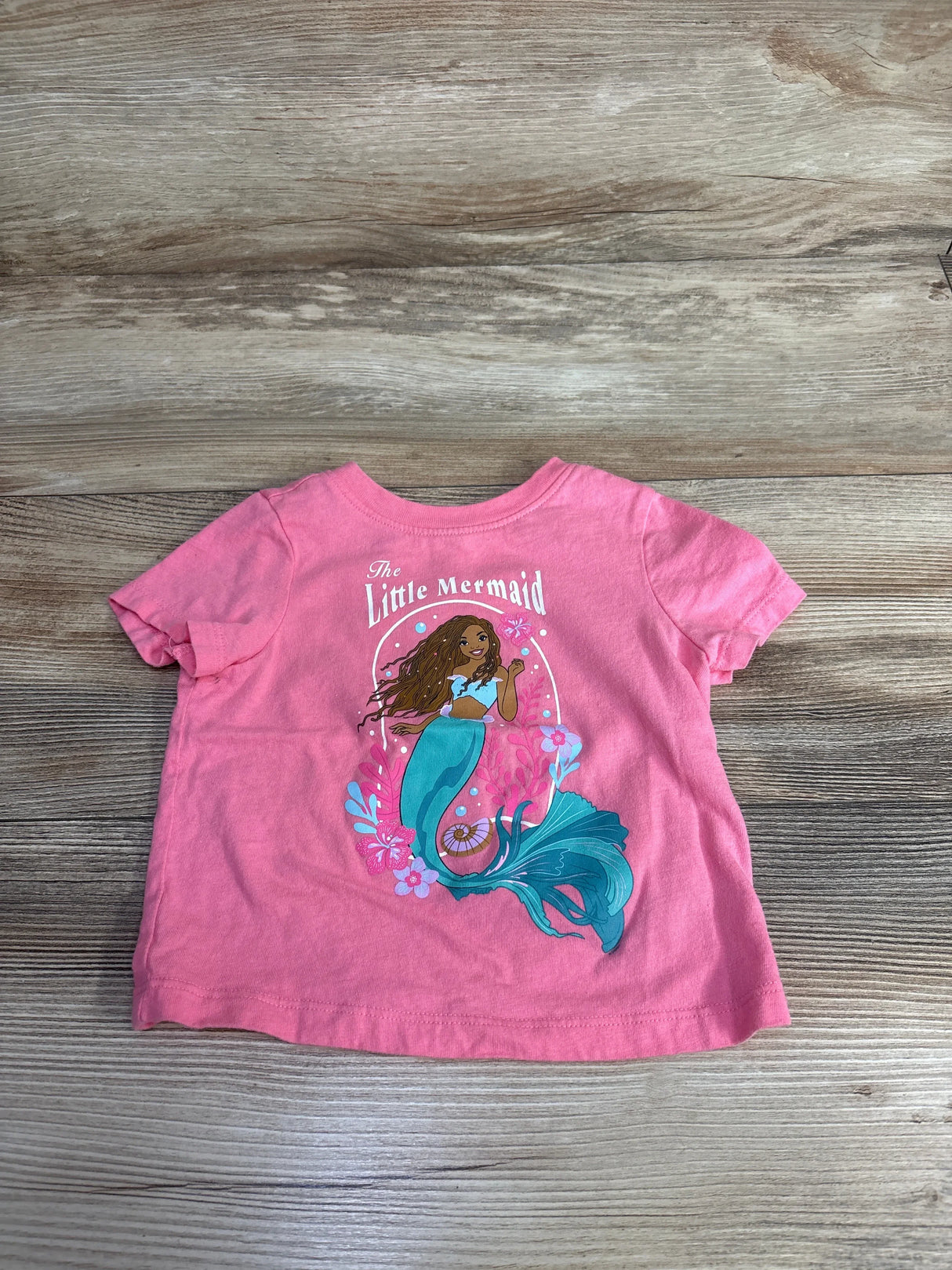 Pink toddler t-shirt with The Little Mermaid graphic, short sleeves, wood background