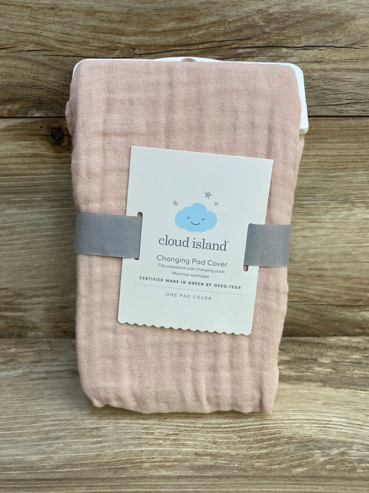 Front view of Cloud Island pink muslin changing pad cover, textured gauze fabric, product tag on wood background