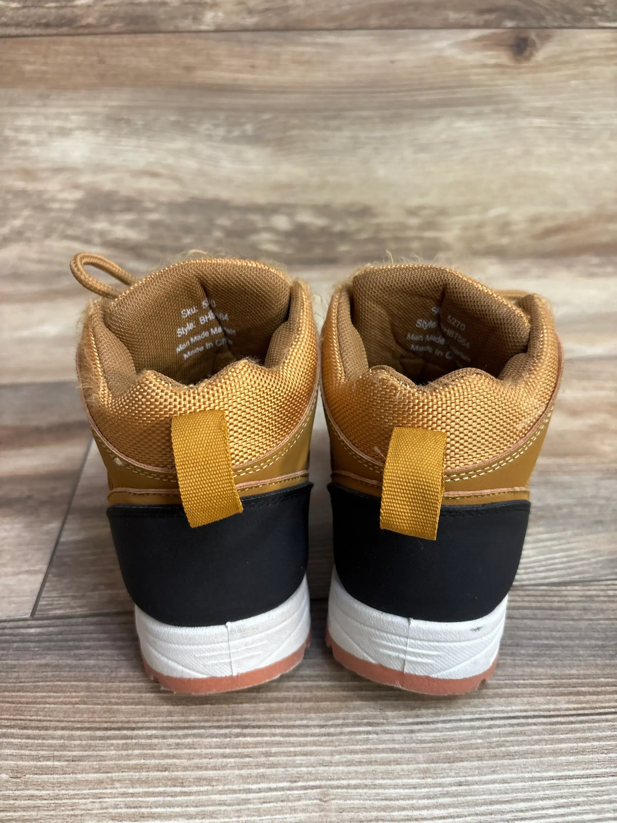 Back view of tan and black toddler boots on wooden floor
