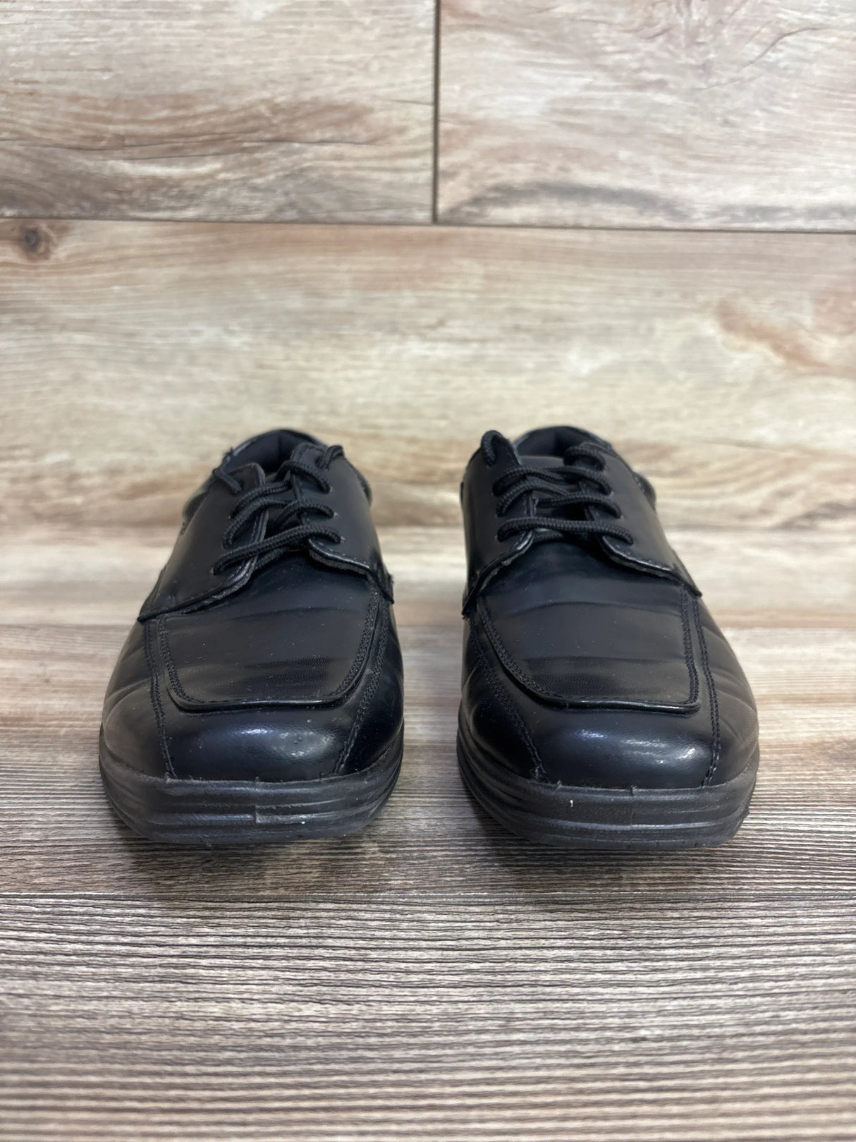 Front view of Deer Stags Sharp black kids lace-up dress shoes size 2Y showing leather upper on wooden floor
