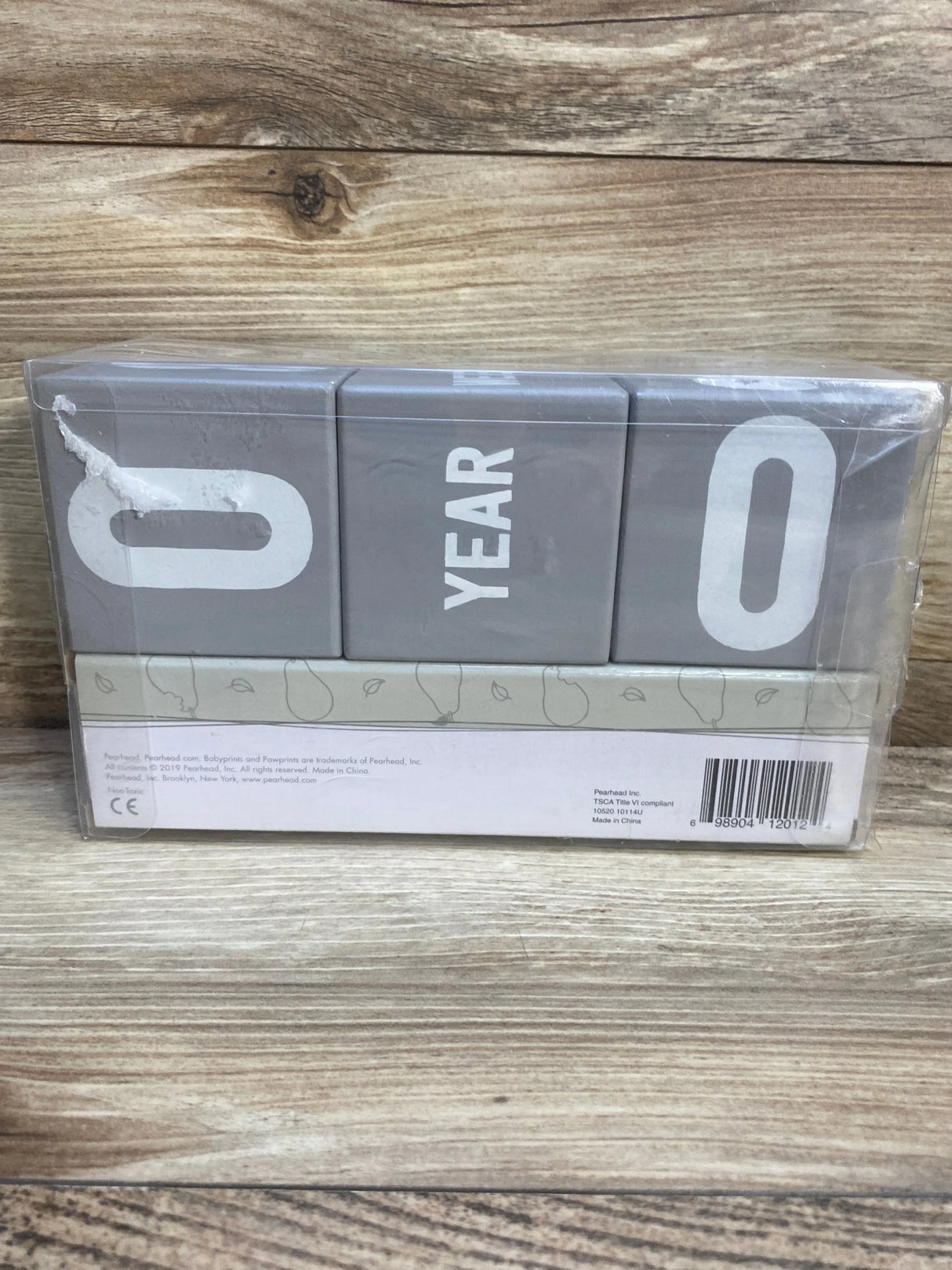 Gray wooden milestone blocks displaying 0 year 0, for baby age tracking on wood background