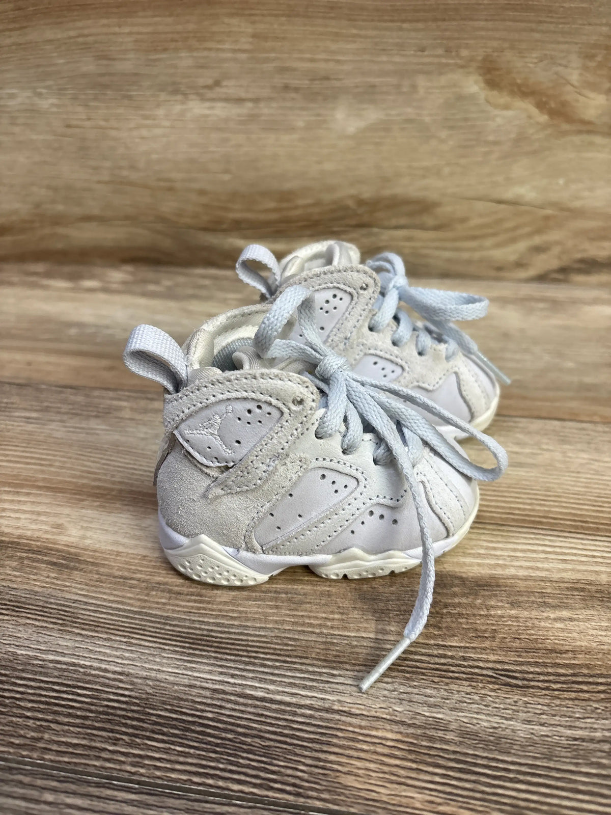 Close-up front view of a pair of Air Jordan 7 Retro TD Cobalt Bliss sneakers size 2C showcasing gray and white panels with laces on wood