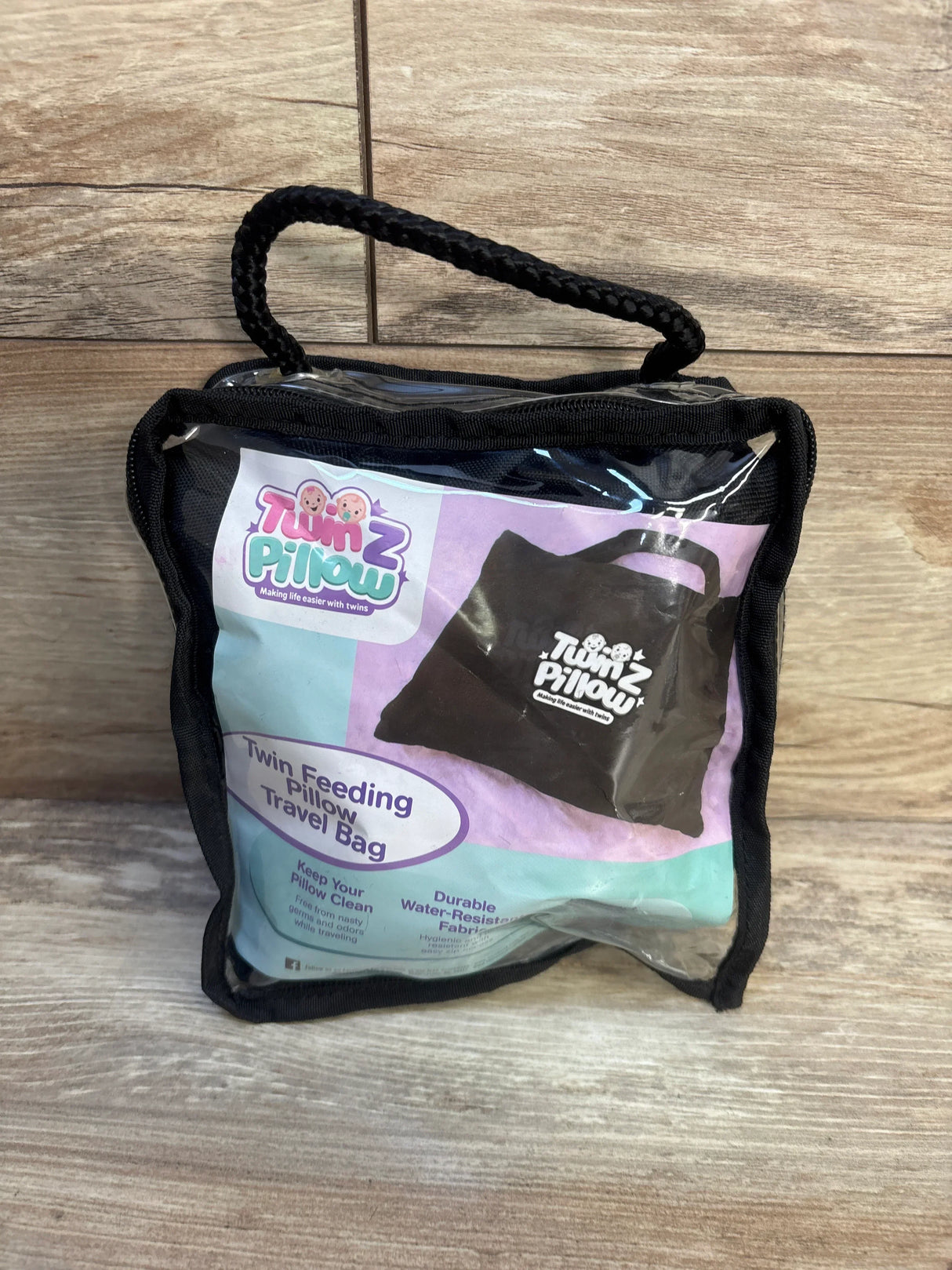 Twin feeding pillow travel bag in clear case on wood floor, durable and water-resistant.
