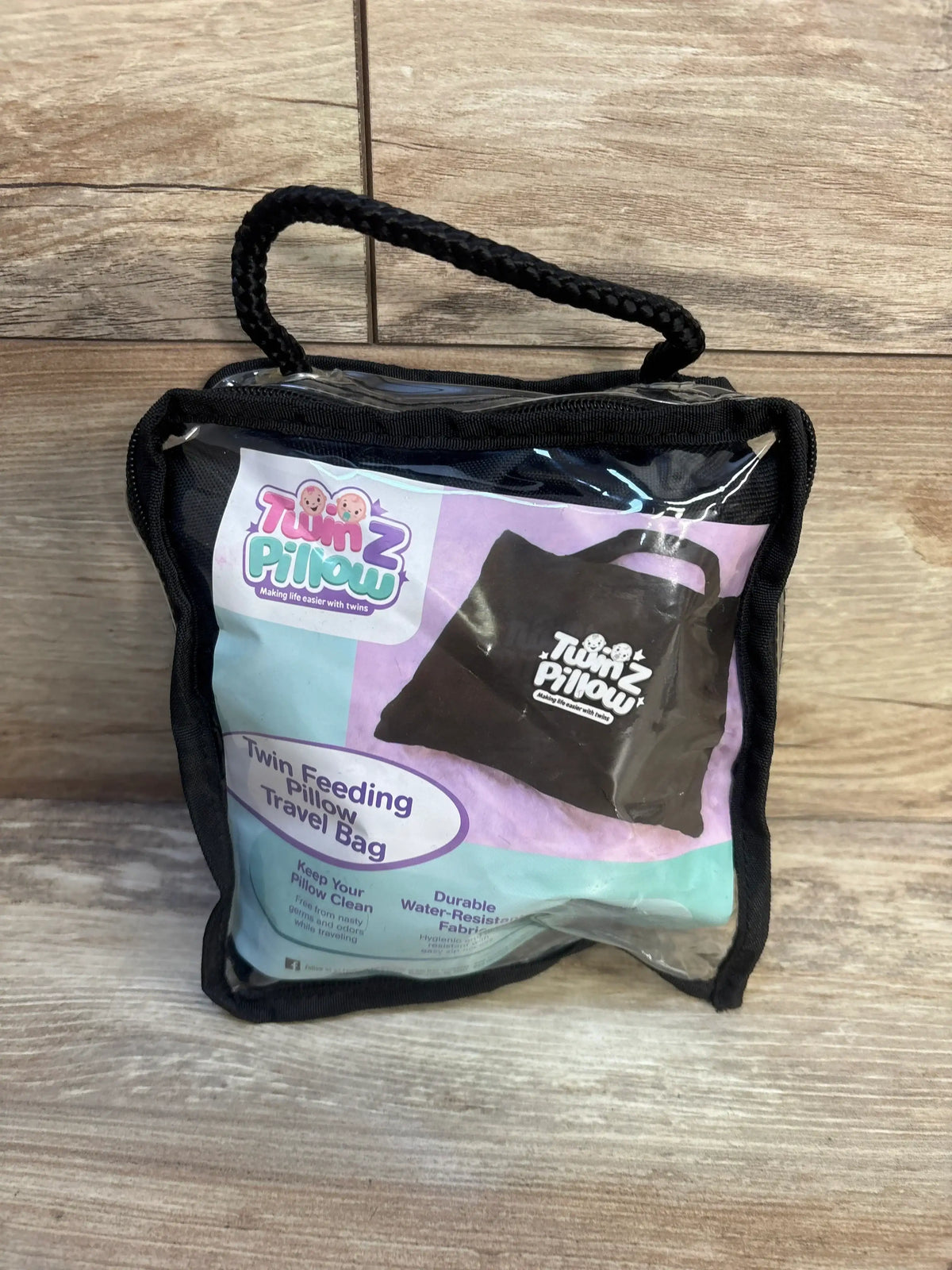 Twin feeding pillow travel bag in clear case on wood floor, durable and water-resistant.