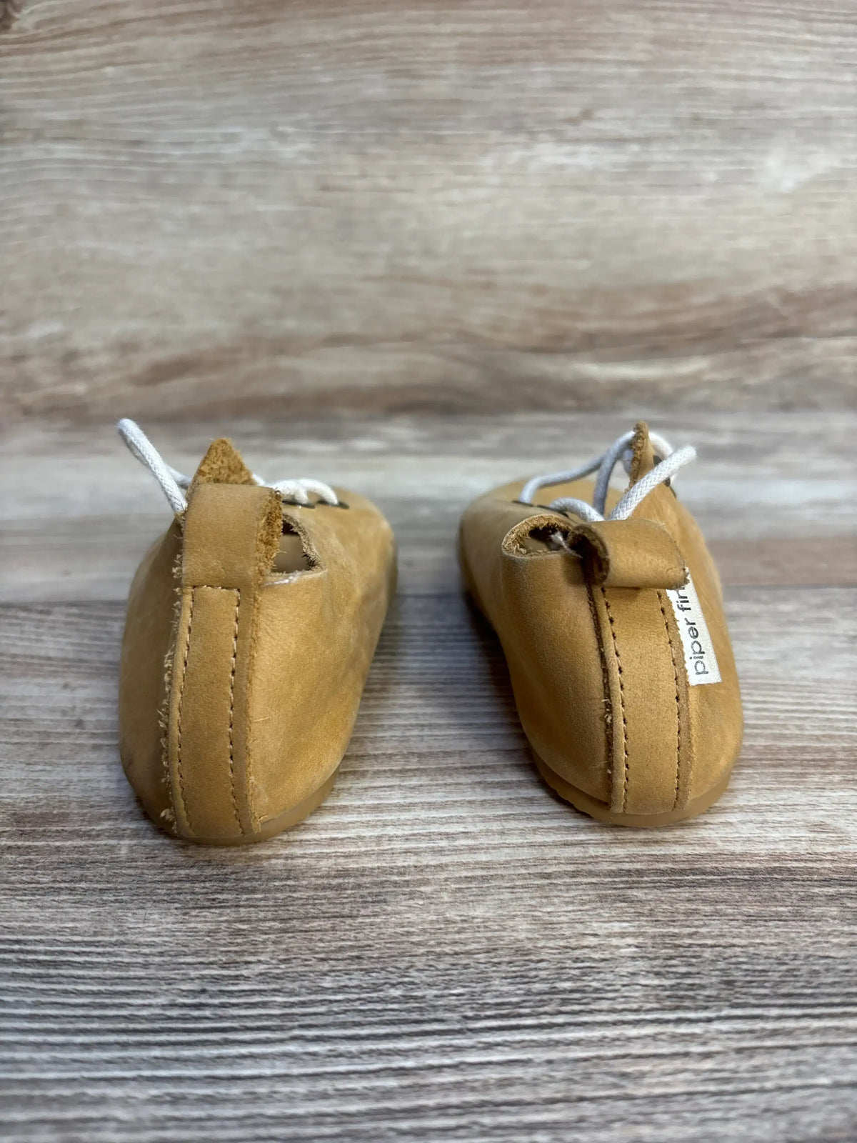 Back view of Piper Finn Natural Low Top Oxfords sz 6c showcasing tan leather uppers white laces and brand tag on wood plank floor