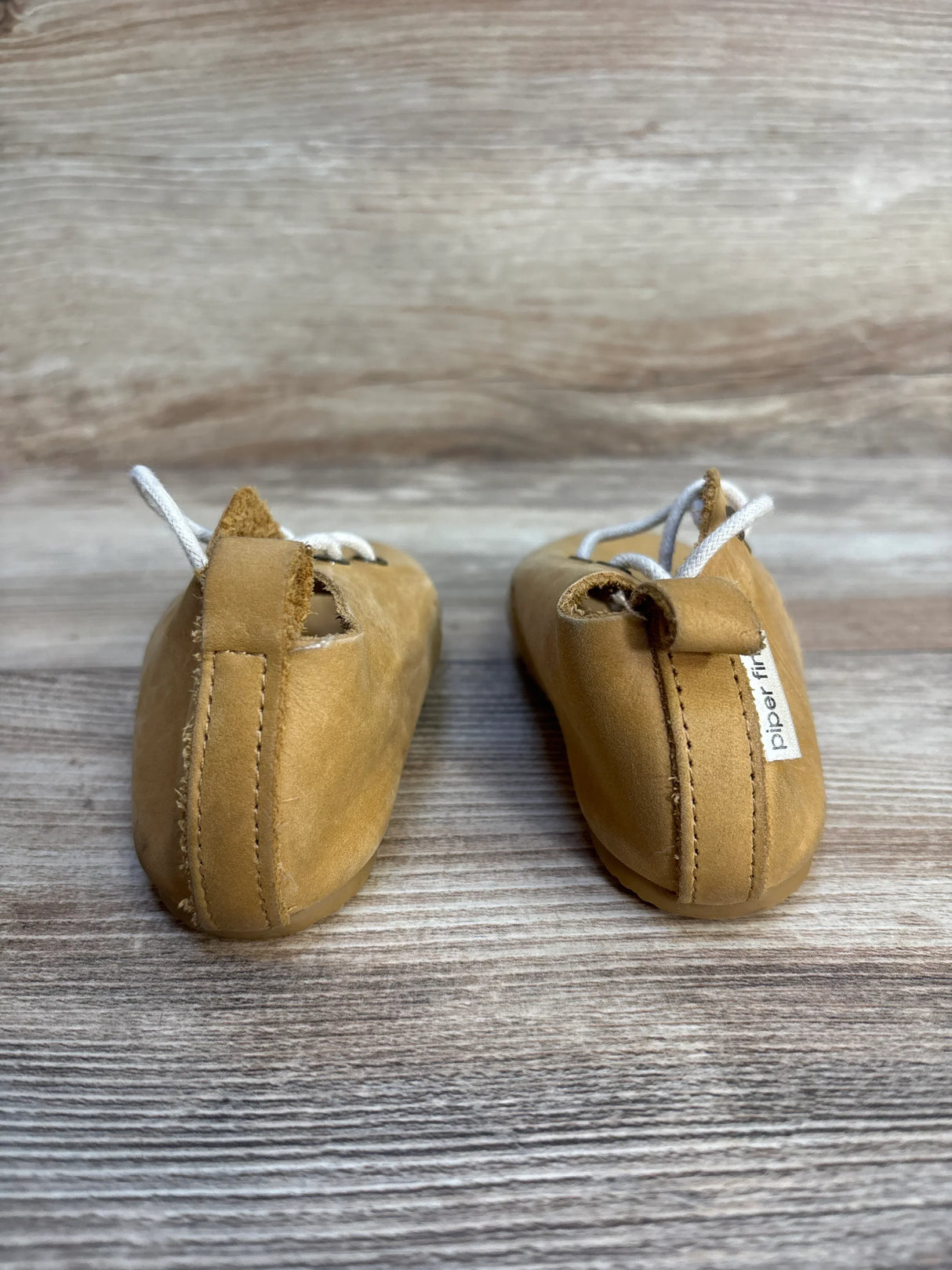 Back view of Piper Finn Natural Low Top Oxfords sz 6c showcasing tan leather uppers white laces and brand tag on wood plank floor