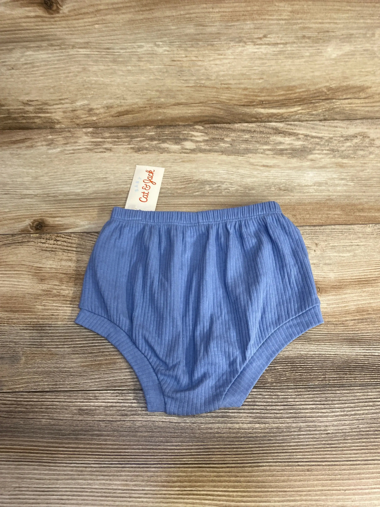 Flat-lay of Cat & Jack blue ribbed baby bloomers size 18 months showing elastic waistband and leg openings on wood background