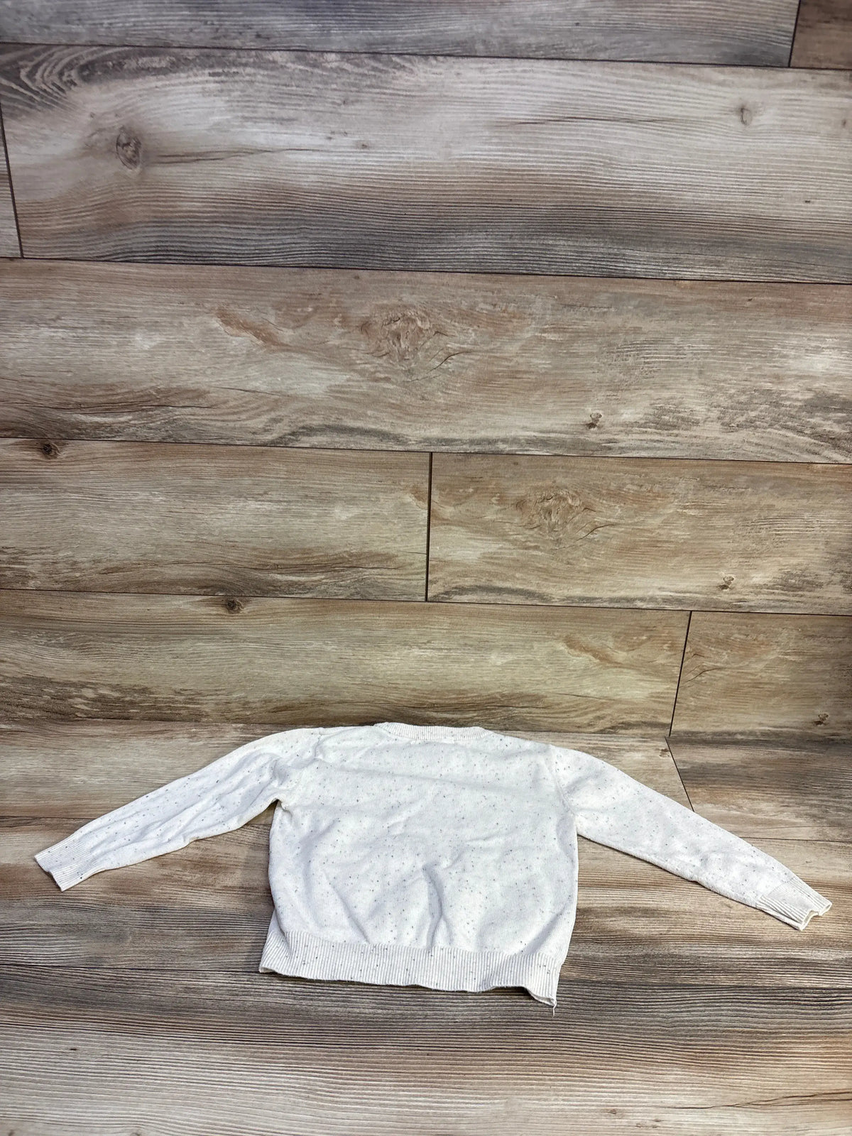 Back view of H&M white fine-knit toddler jumper size 3/4T showing ribbed cuffs and hem and speckled knit on wood background
