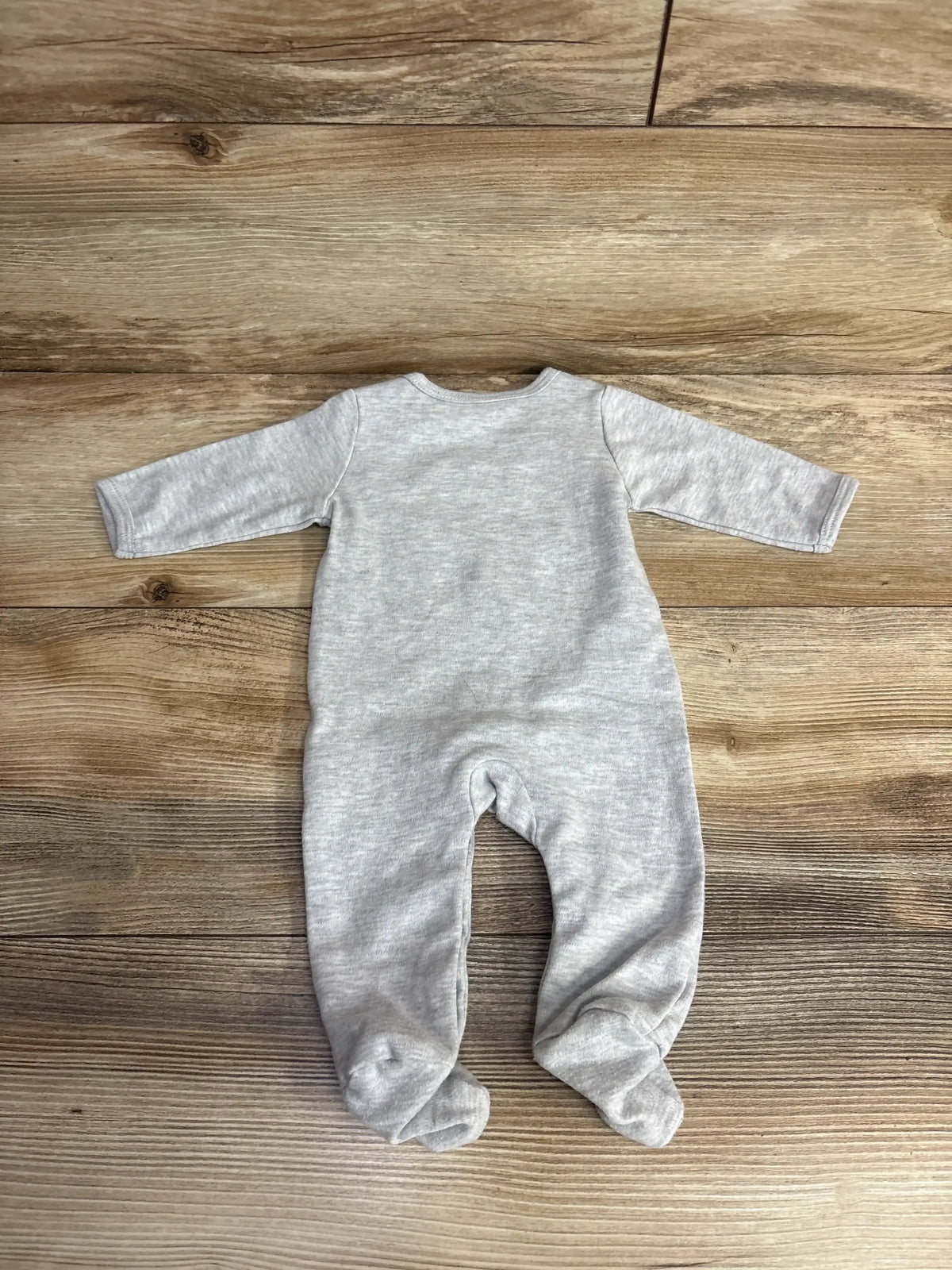 Gray long sleeve baby footed sleeper laid flat on wood floor